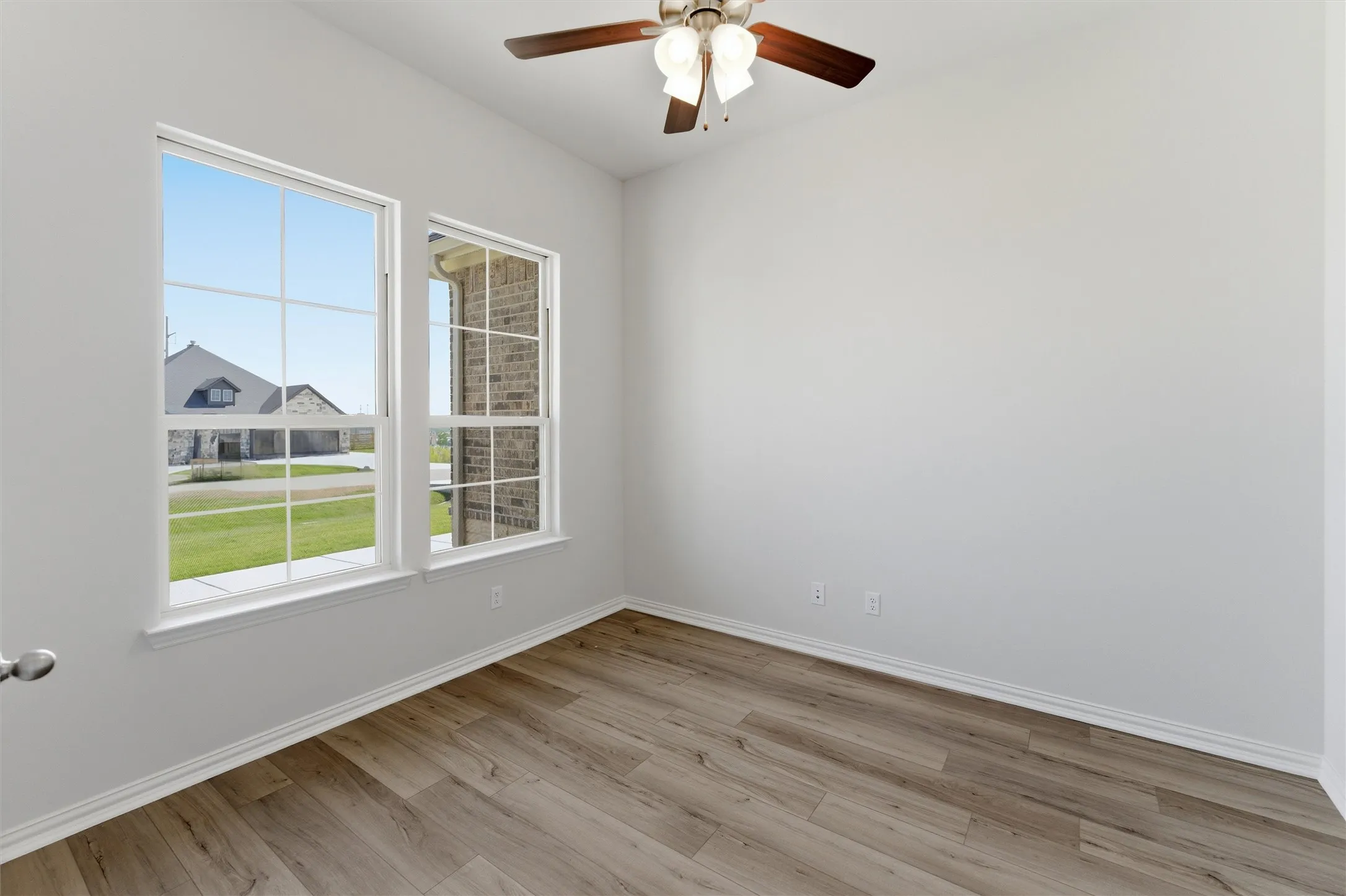 Room featuring a ceiling fan with light fixture, wood-finish flooring, and white baseboards
