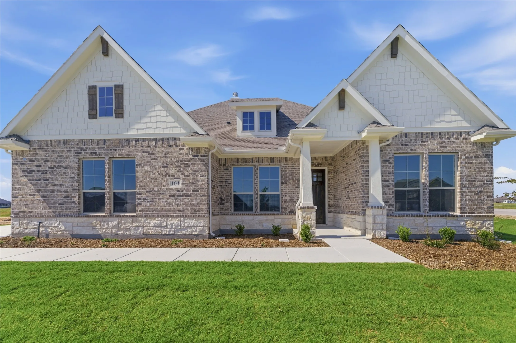 Traditional-style residence featuring a prominent brick and stone facade