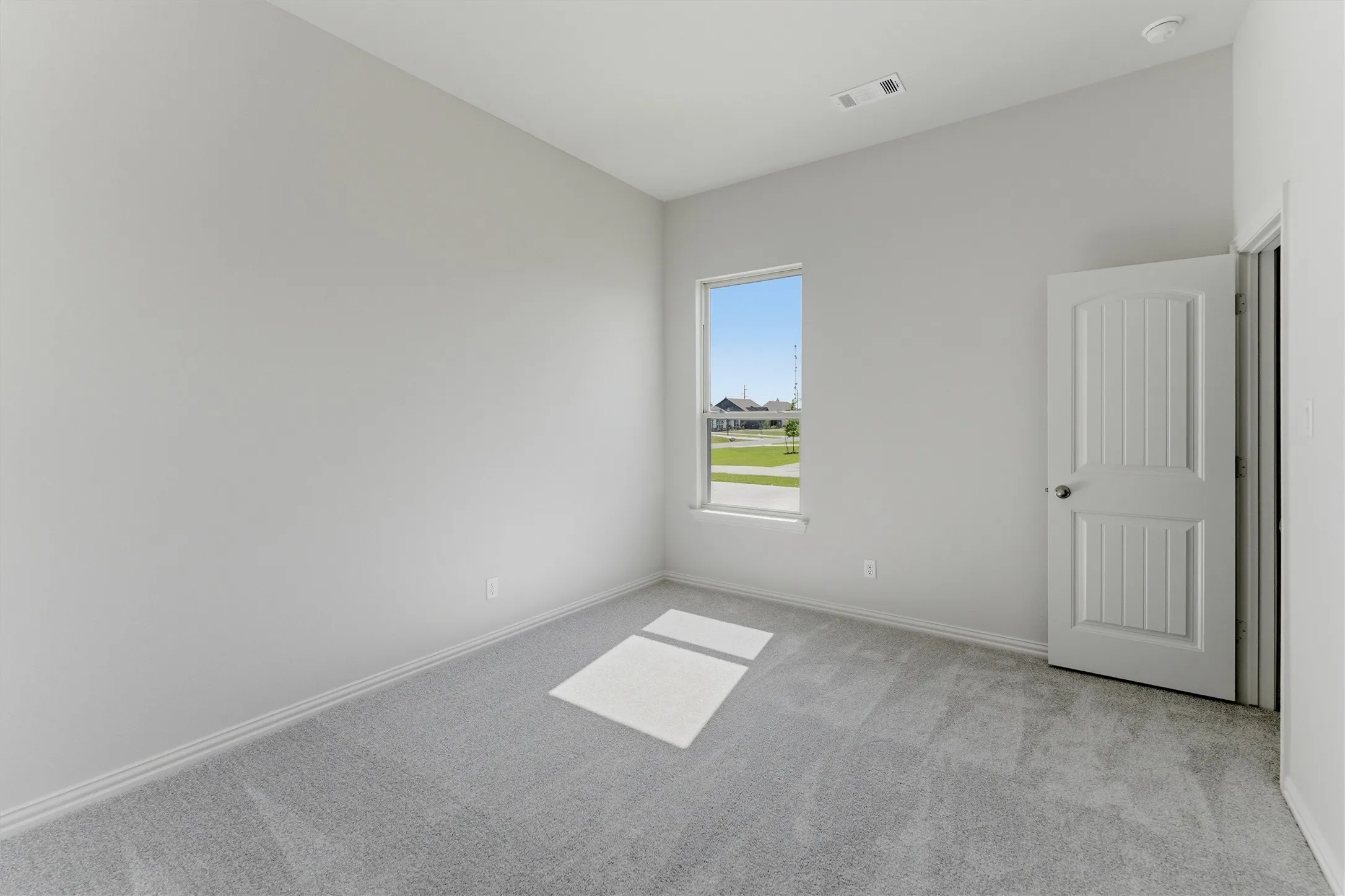 Interior room featuring light gray carpeting, white baseboards, and a single window offering exterior views
