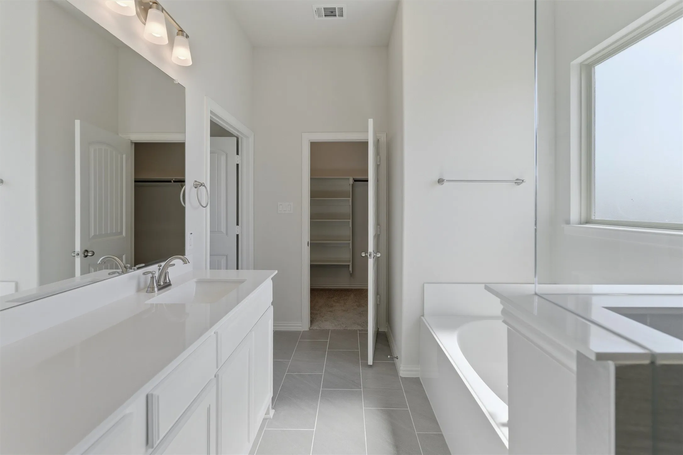 Bathroom featuring a double vanity with white cabinetry, integrated sinks, and polished chrome fixtures