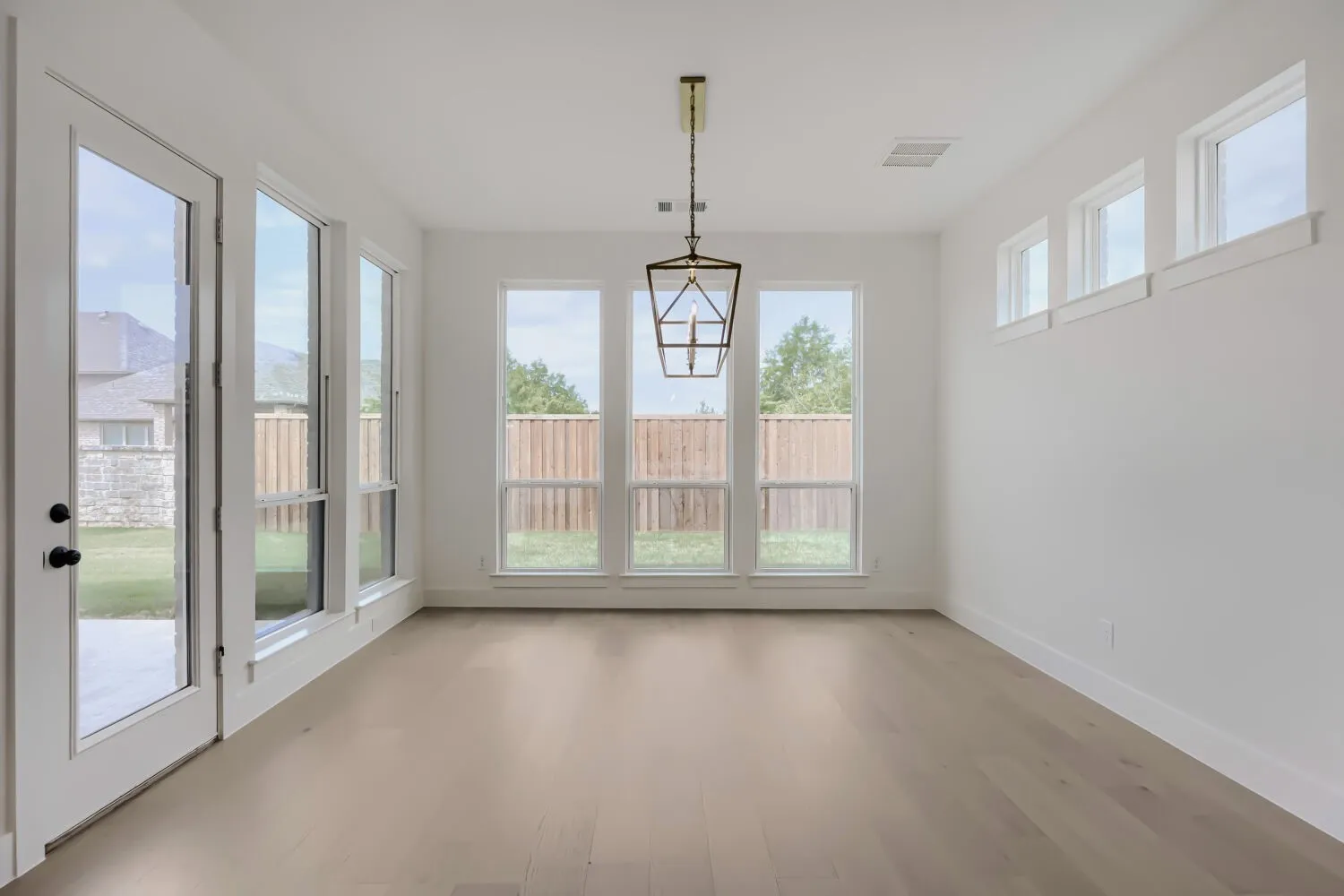 Room with wood-finish flooring, white walls, and multiple windows