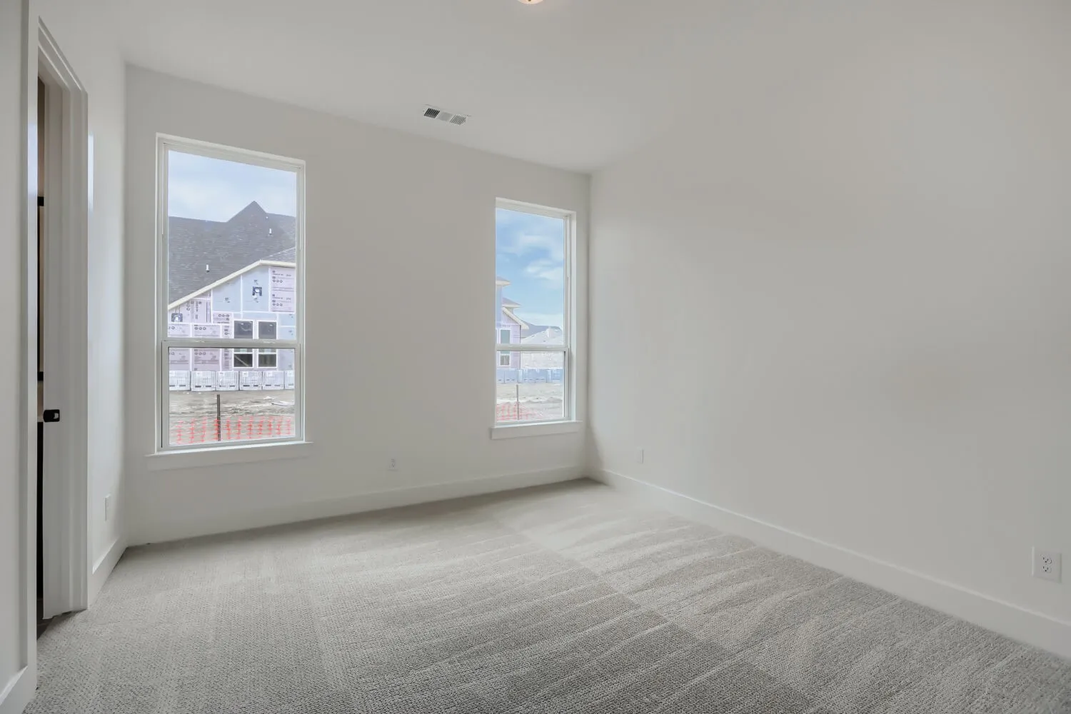 Spacious room featuring neutral paint, gray patterned carpet, and dual windows