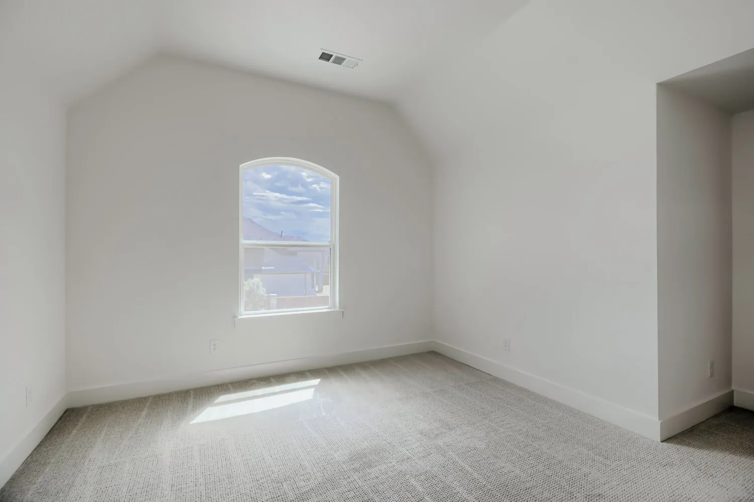 Room with vaulted ceiling, arched window, light gray carpeting, crisp white walls, and white baseboards