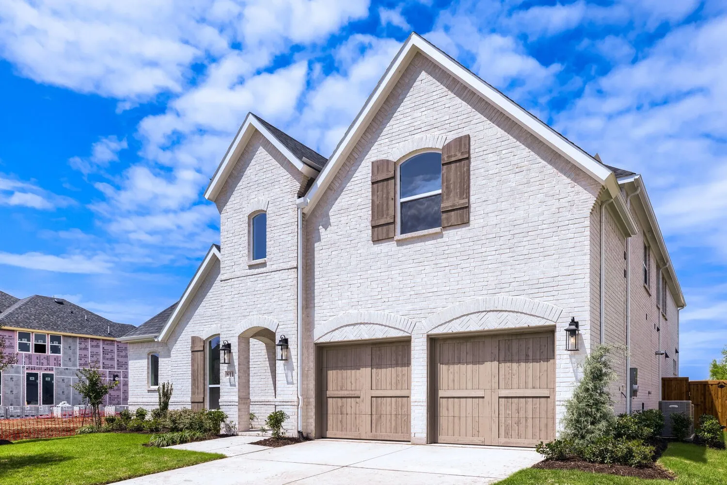 Two-story residence featuring a white brick exterior, gabled rooflines, and decorative wood shutters