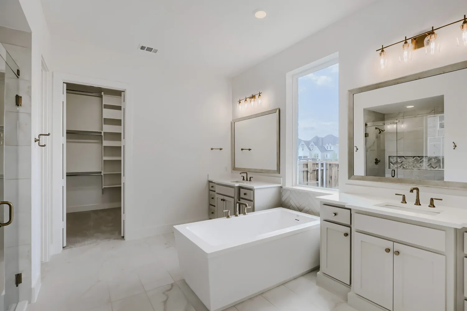 Bathroom featuring a freestanding soaking tub, dual vanities with integrated sinks, and a separate glass-enclosed shower