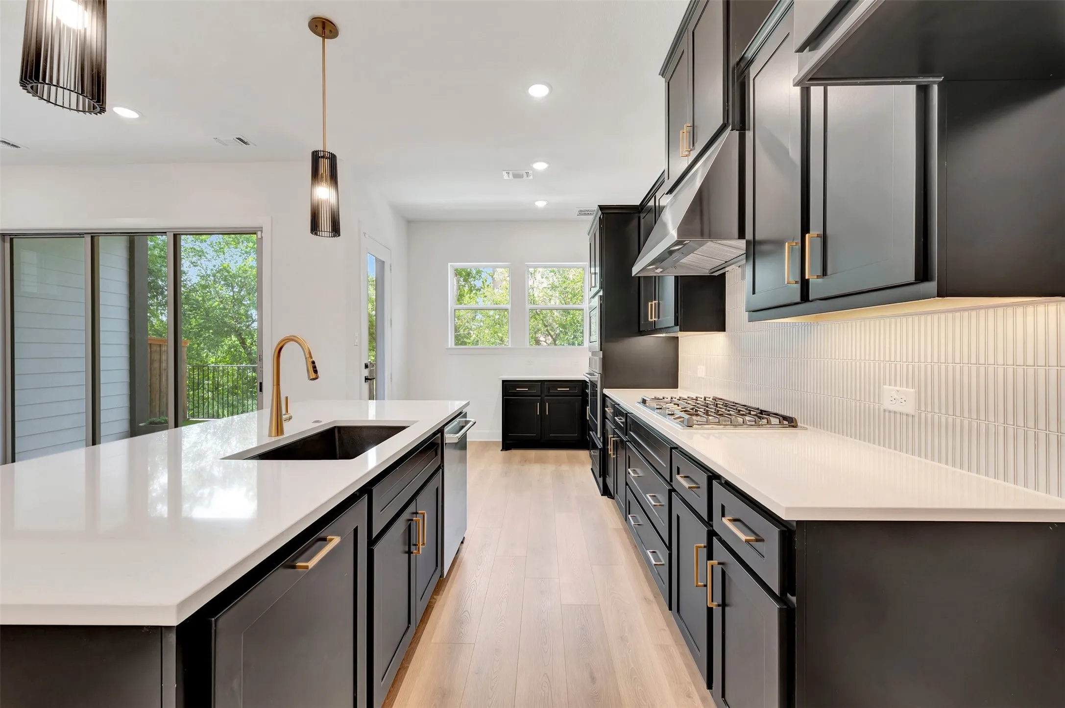 Modern kitchen featuring dark cabinetry, white countertops, and a full suite of stainless steel appliances