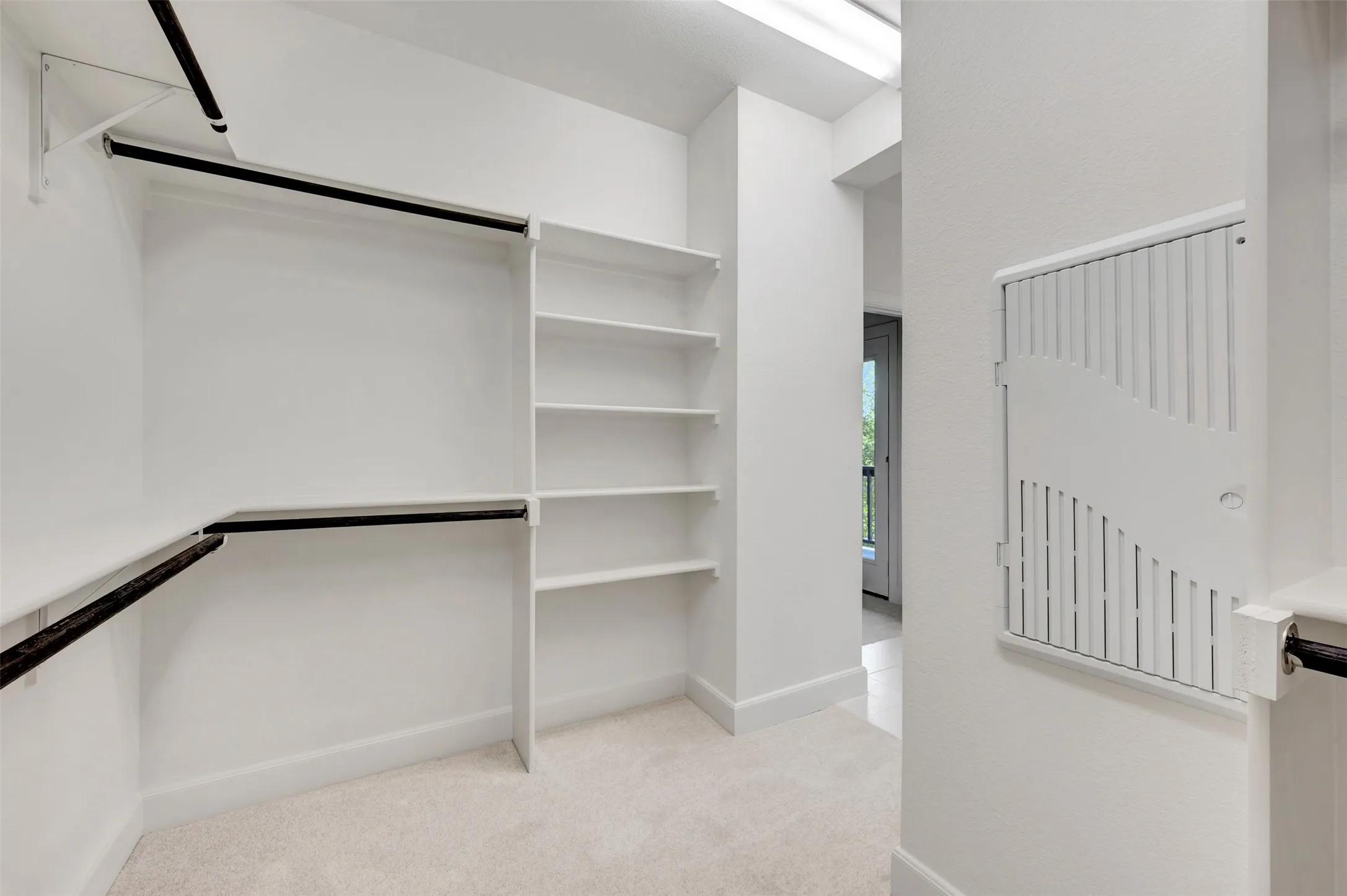 Walk-in closet featuring extensive built-in shelving, multiple hanging rods, and light-toned carpeting