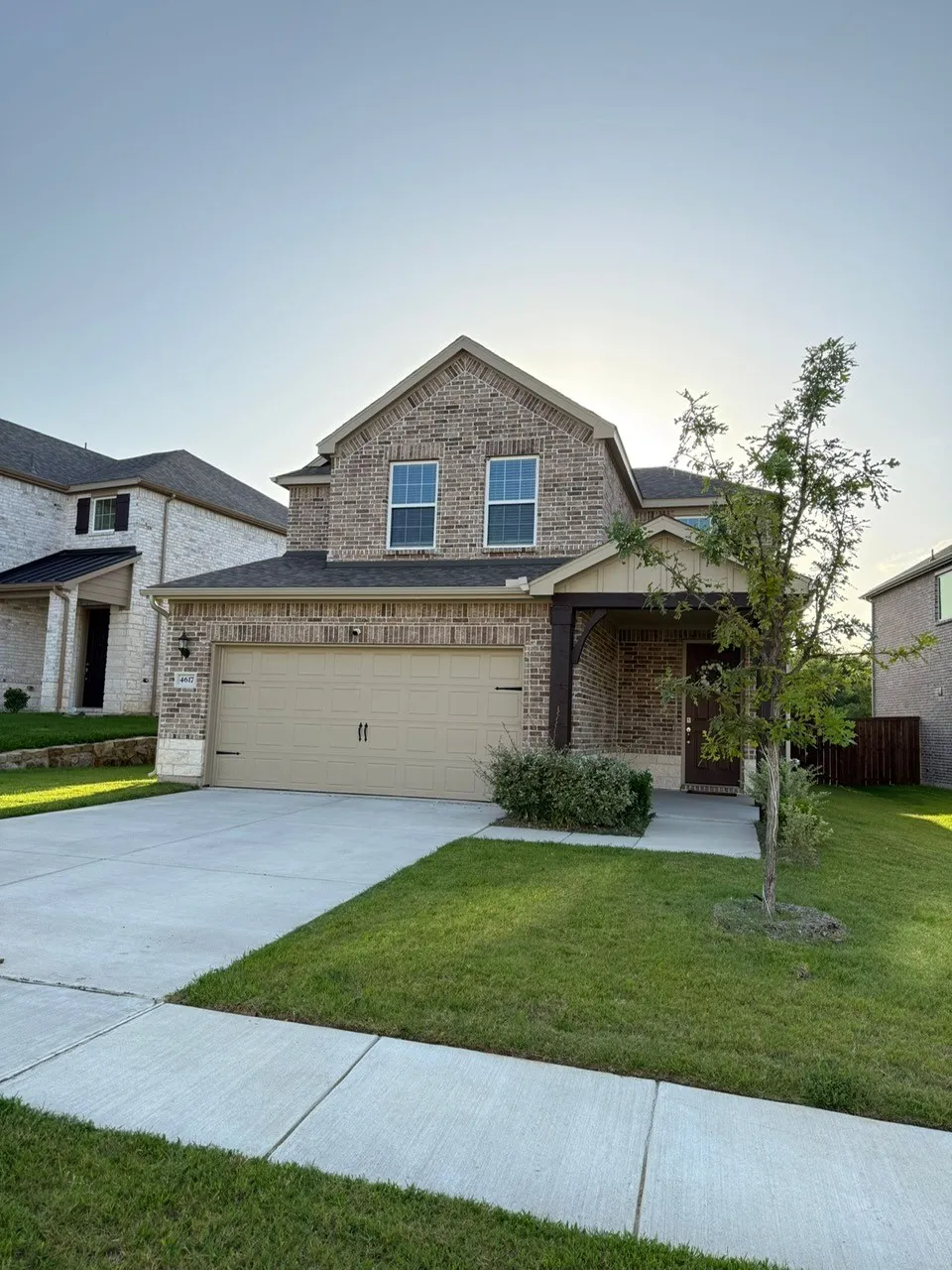View of front of house featuring brick siding, an attached garage, concrete driveway, and a front lawn
