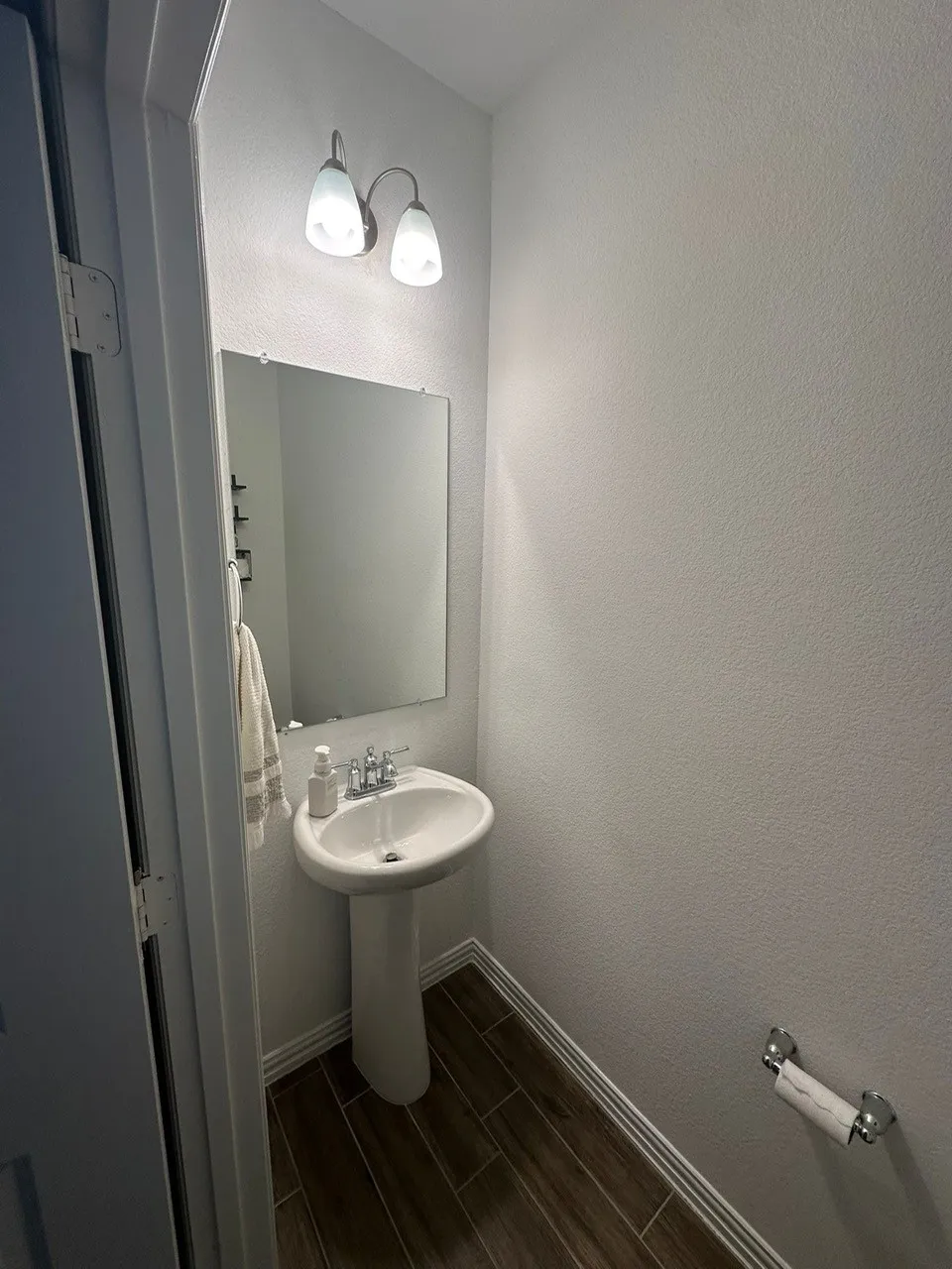 Half bathroom with wood tiled floors and a textured wall