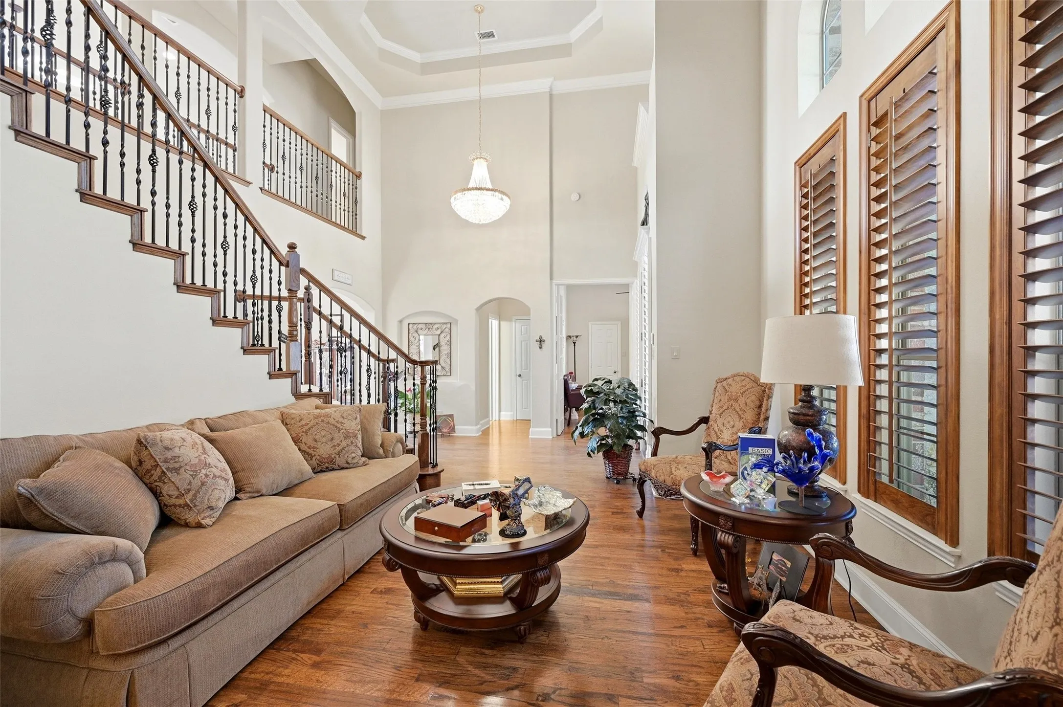 Living room with wood finished floors, arched walkways, stairway, a towering ceiling, and healthy amount of natural light
