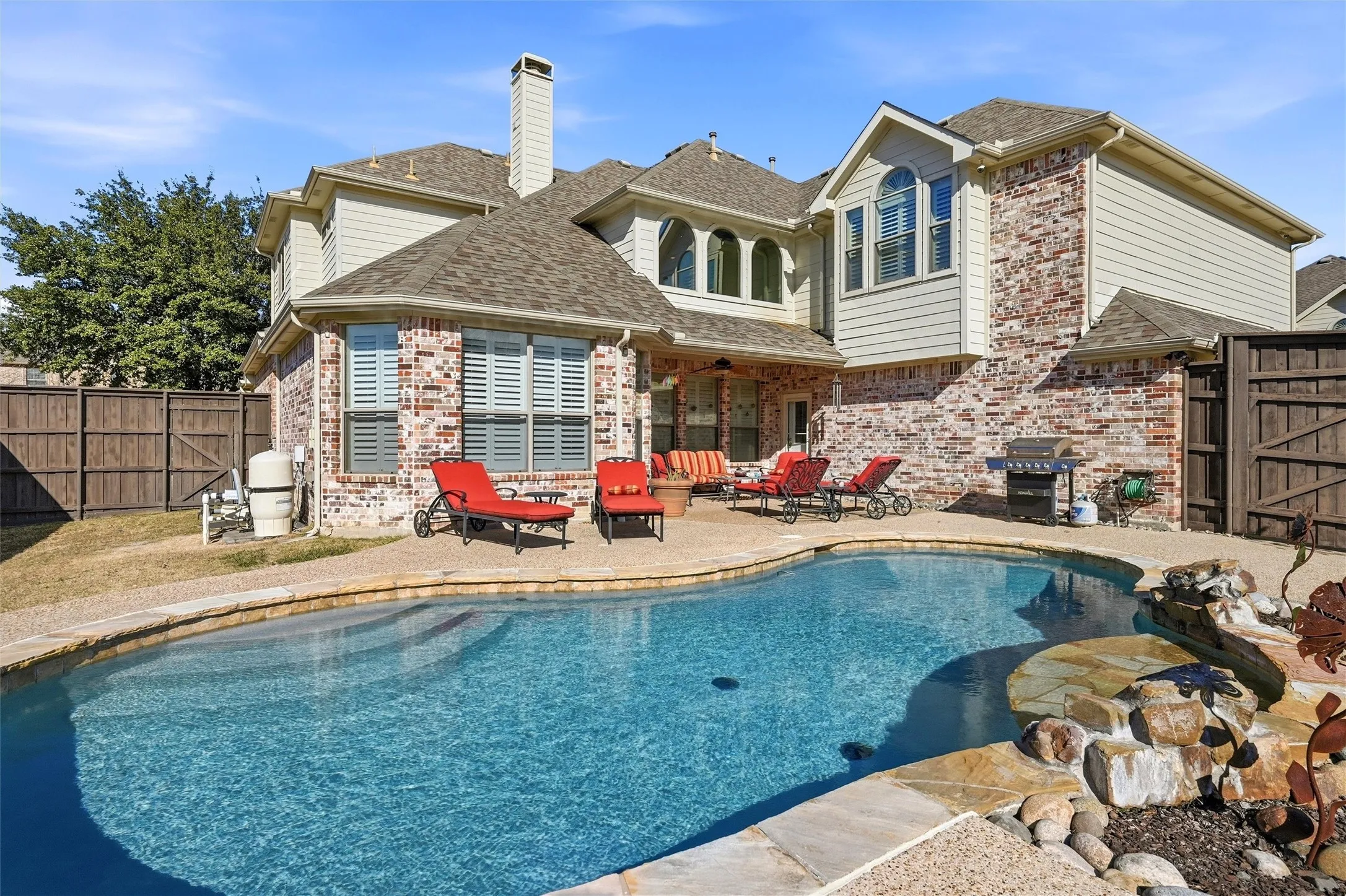 Back of property featuring a patio area, a fenced backyard, a shingled roof, brick siding, and a chimney