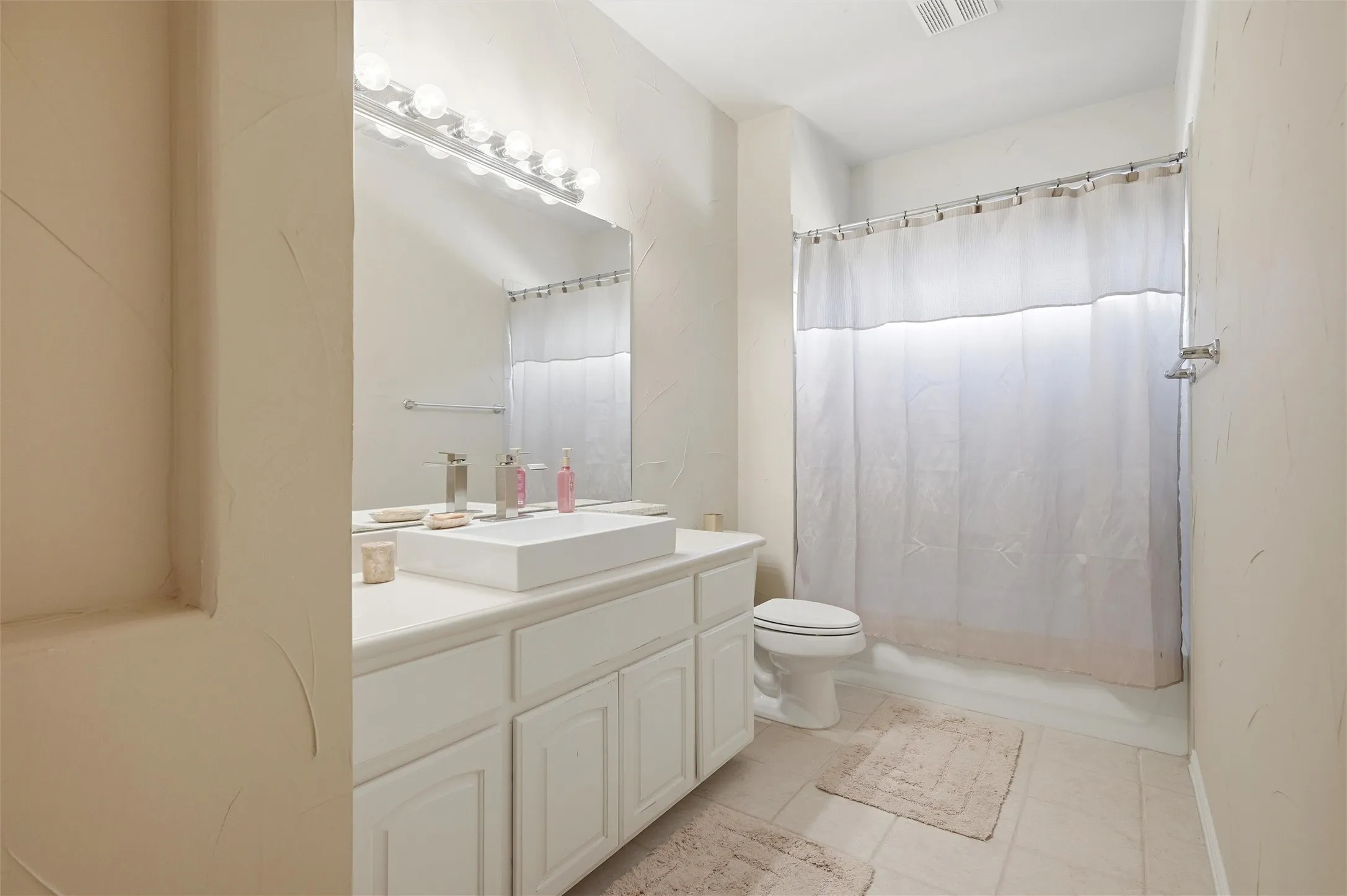 Full bath featuring vanity, light tile patterned flooring, and shower / tub combo with curtain