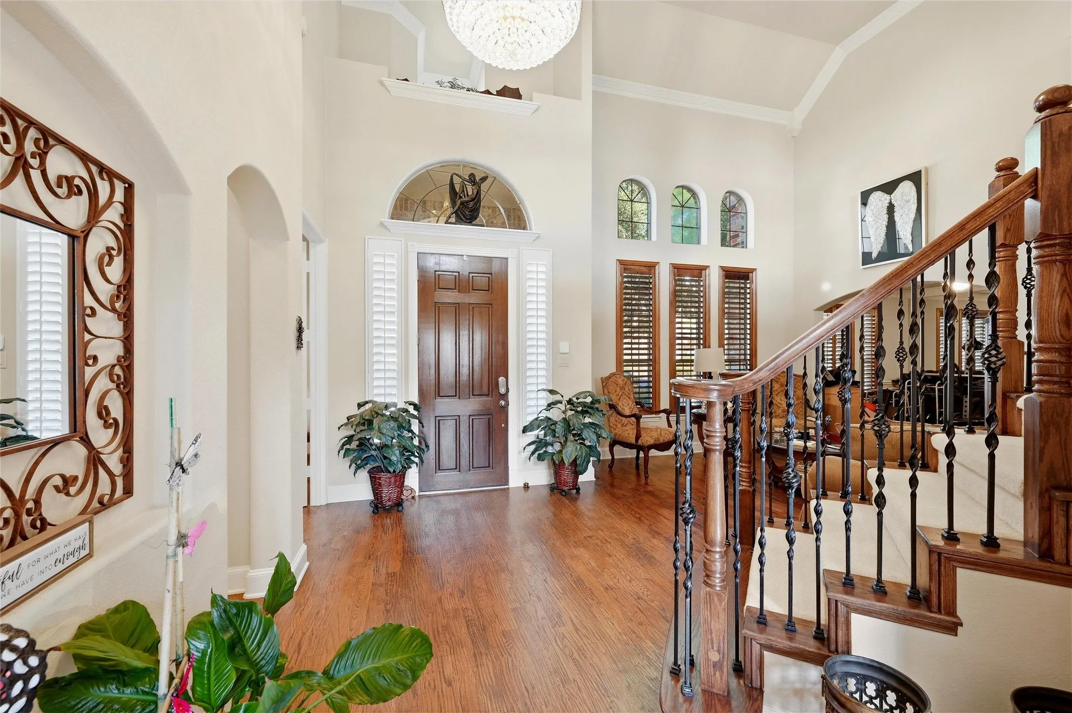 Entryway with wood finished floors, high vaulted ceiling, healthy amount of natural light, crown molding, and stairway