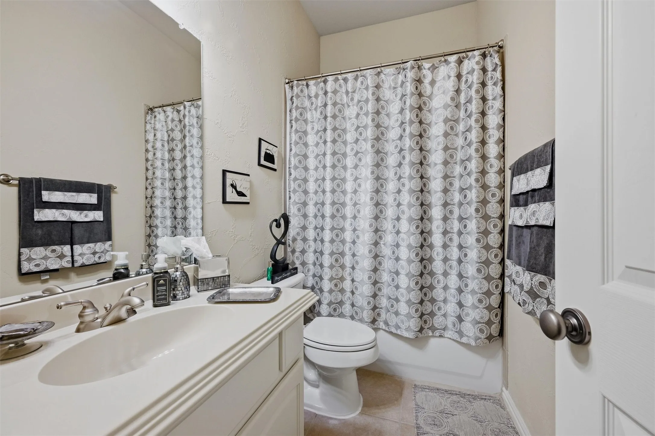 Full bathroom with vanity, light tile patterned flooring, shower / tub combo with curtain, and a textured wall