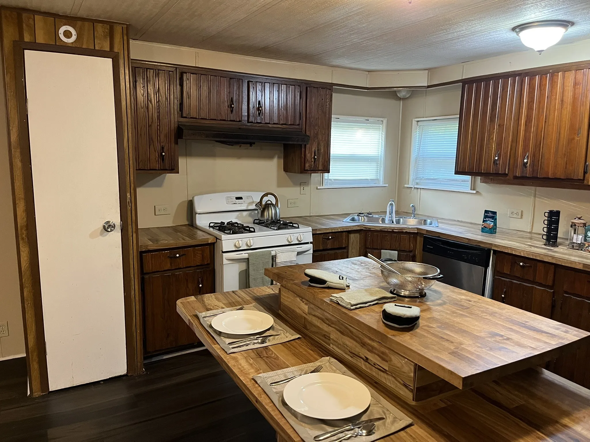 Kitchen featuring dark brown cabinets, white gas range oven, dark wood finished floors, stainless steel dishwasher, and under cabinet range hood