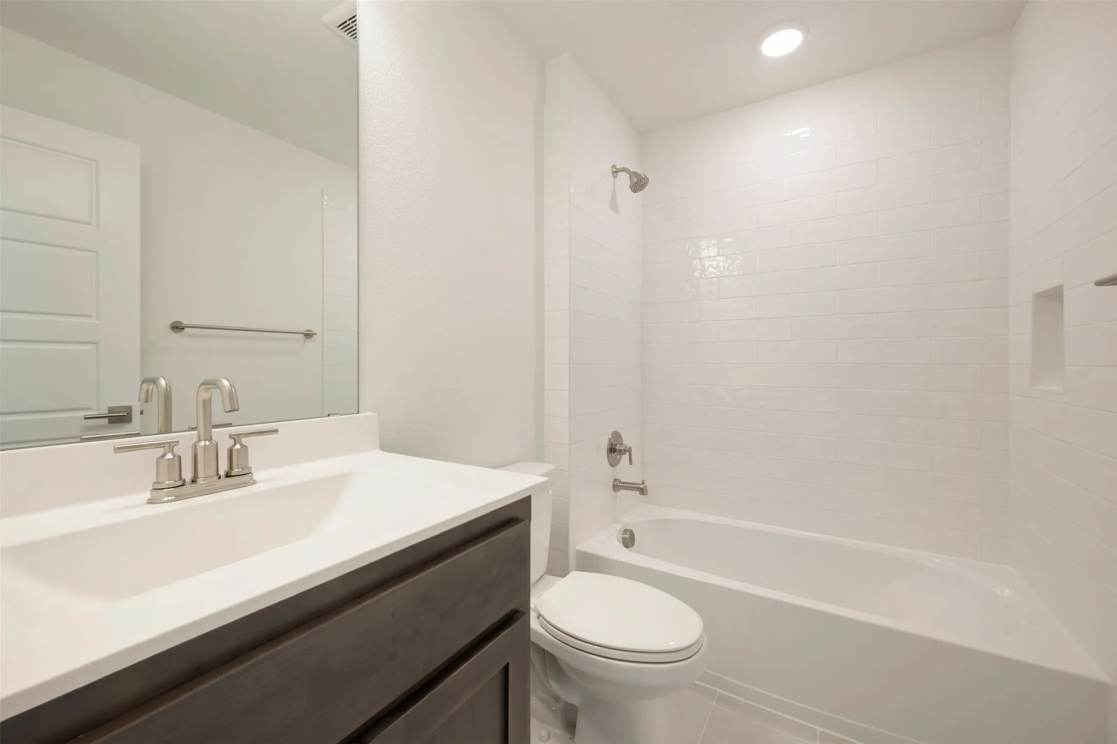 Bathroom featuring a single vanity with a dark wood-finish cabinet, white countertop, and brushed nickel faucet