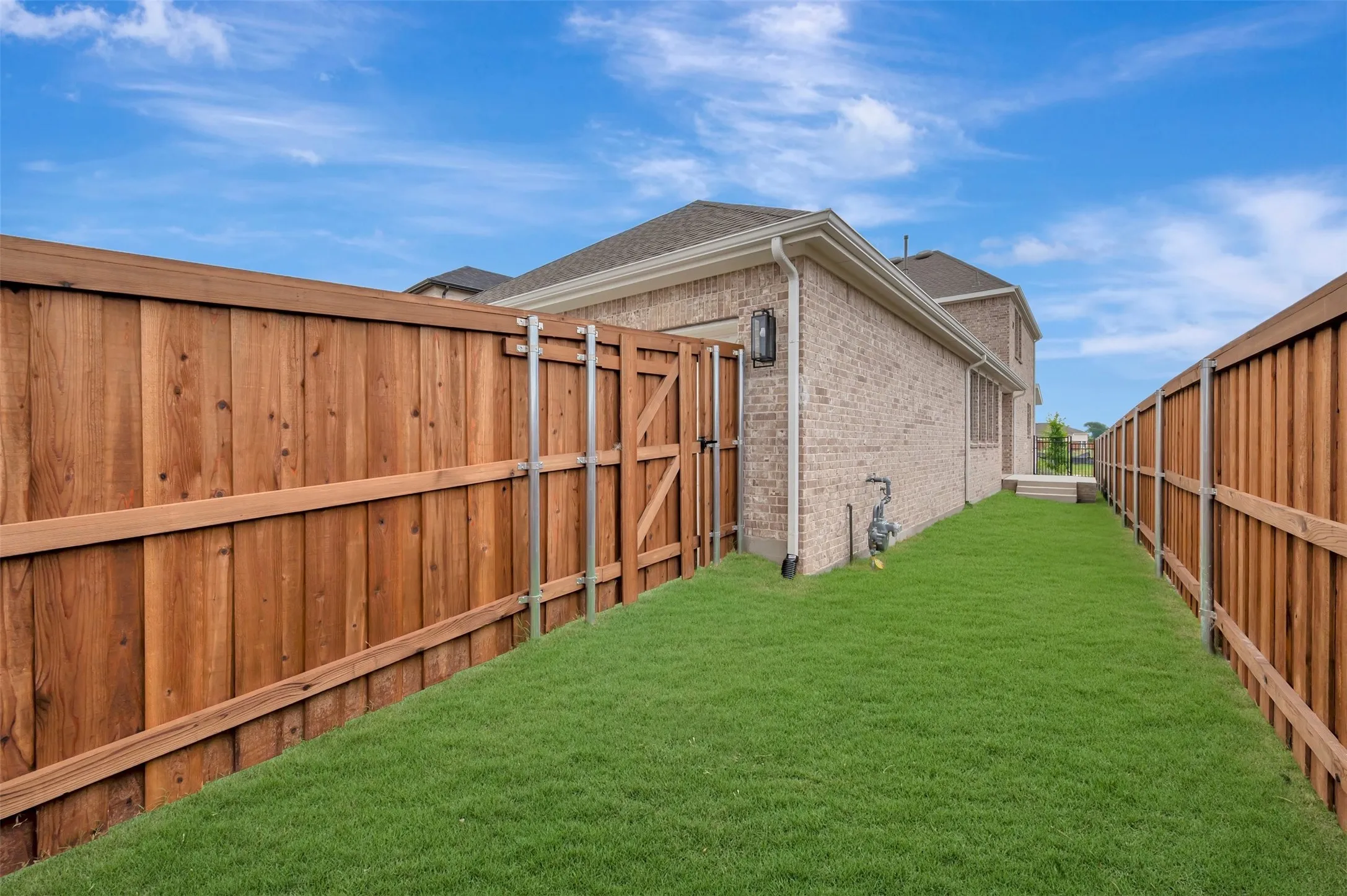 Side yard featuring a manicured lawn, full privacy fencing, and a brick exterior