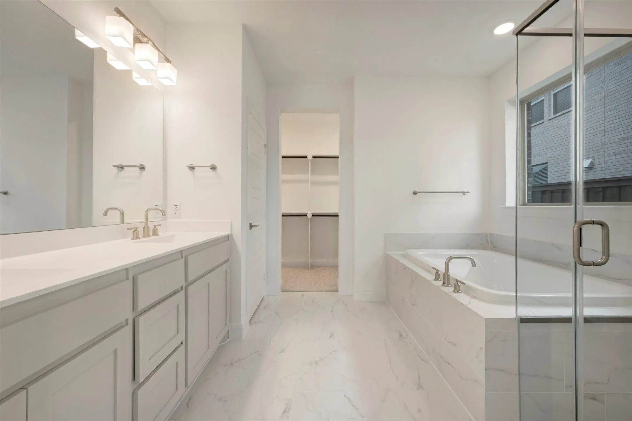 Bathroom featuring a dual vanity with light gray cabinetry, a large mirror, and contemporary lighting