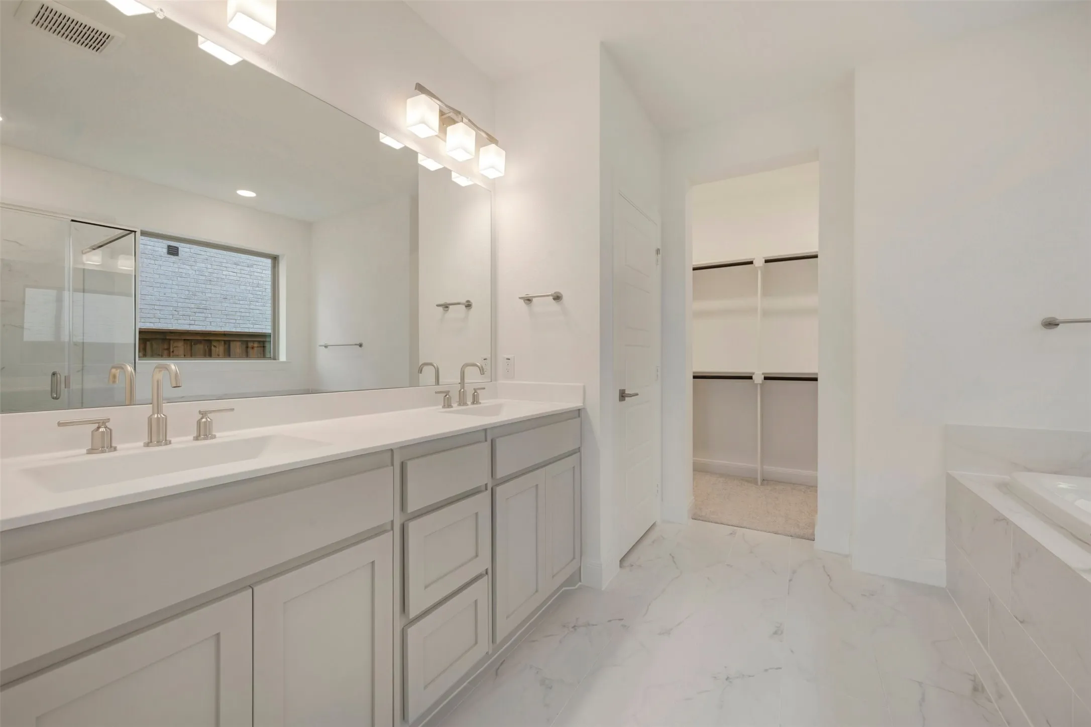 Bathroom featuring a dual vanity with light cabinetry and white countertops, brushed nickel fixtures, a large mirror, and overhead lighting