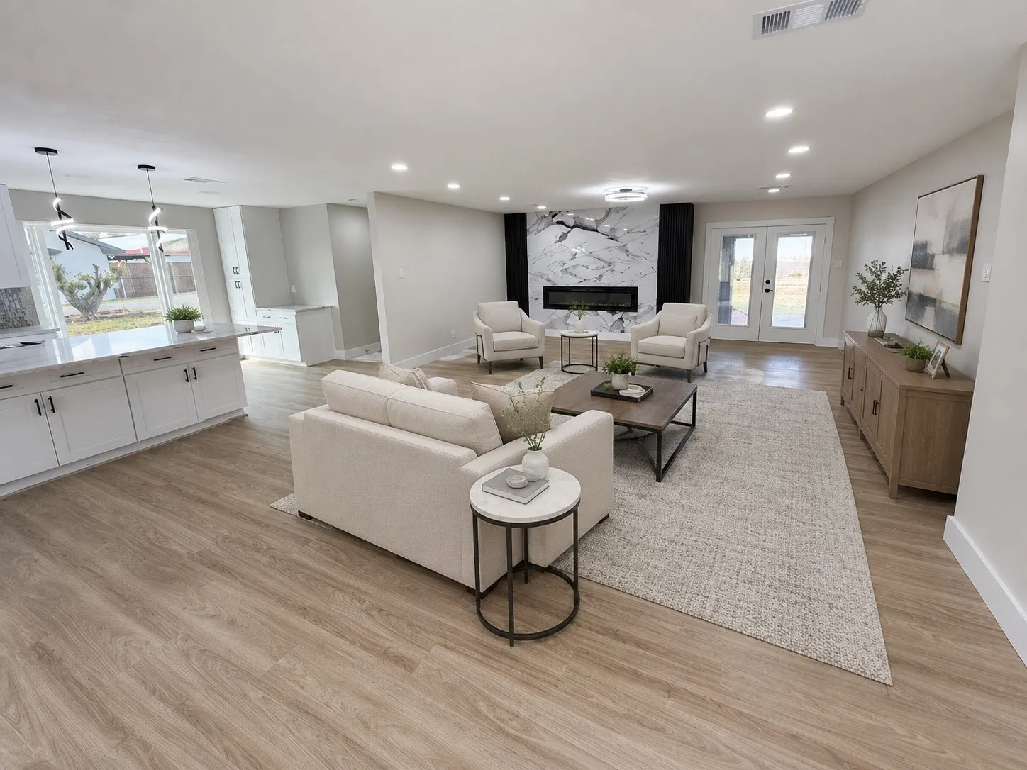 Open-concept living area featuring wood-finish flooring, recessed lighting, and a modern fireplace with a marble-patterned surround
