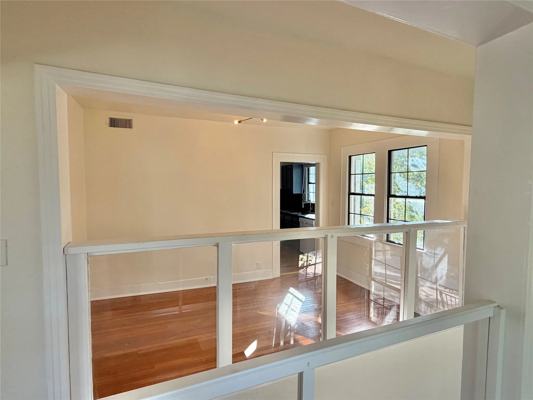 Wood-finish flooring throughout, framed by a half-wall with clear panels, and a large window with divided lites