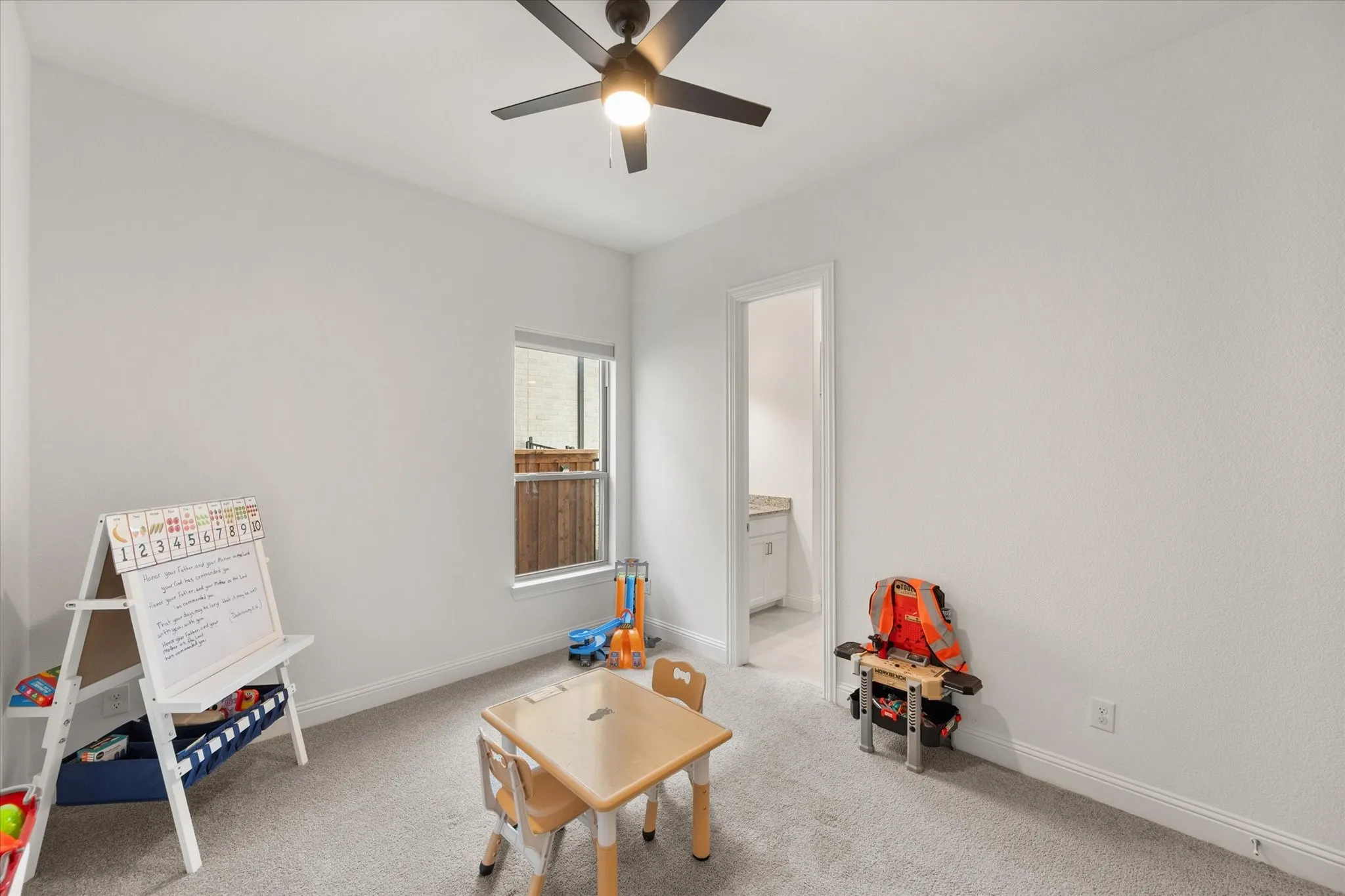Secondary bedroom with light colored carpet and ceiling fan