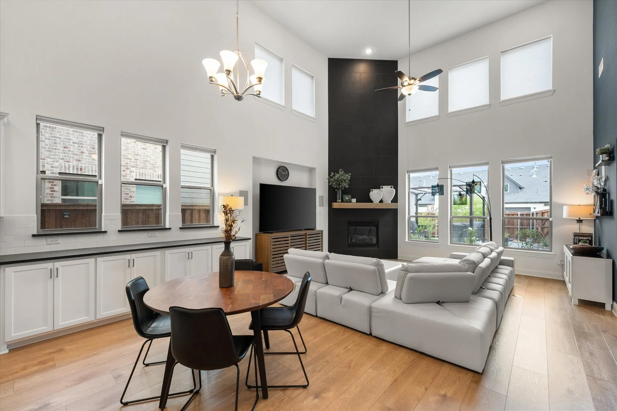 Living room featuring a large fireplace, a high ceiling, a ceiling fan, plenty of natural light, and light wood-type flooring