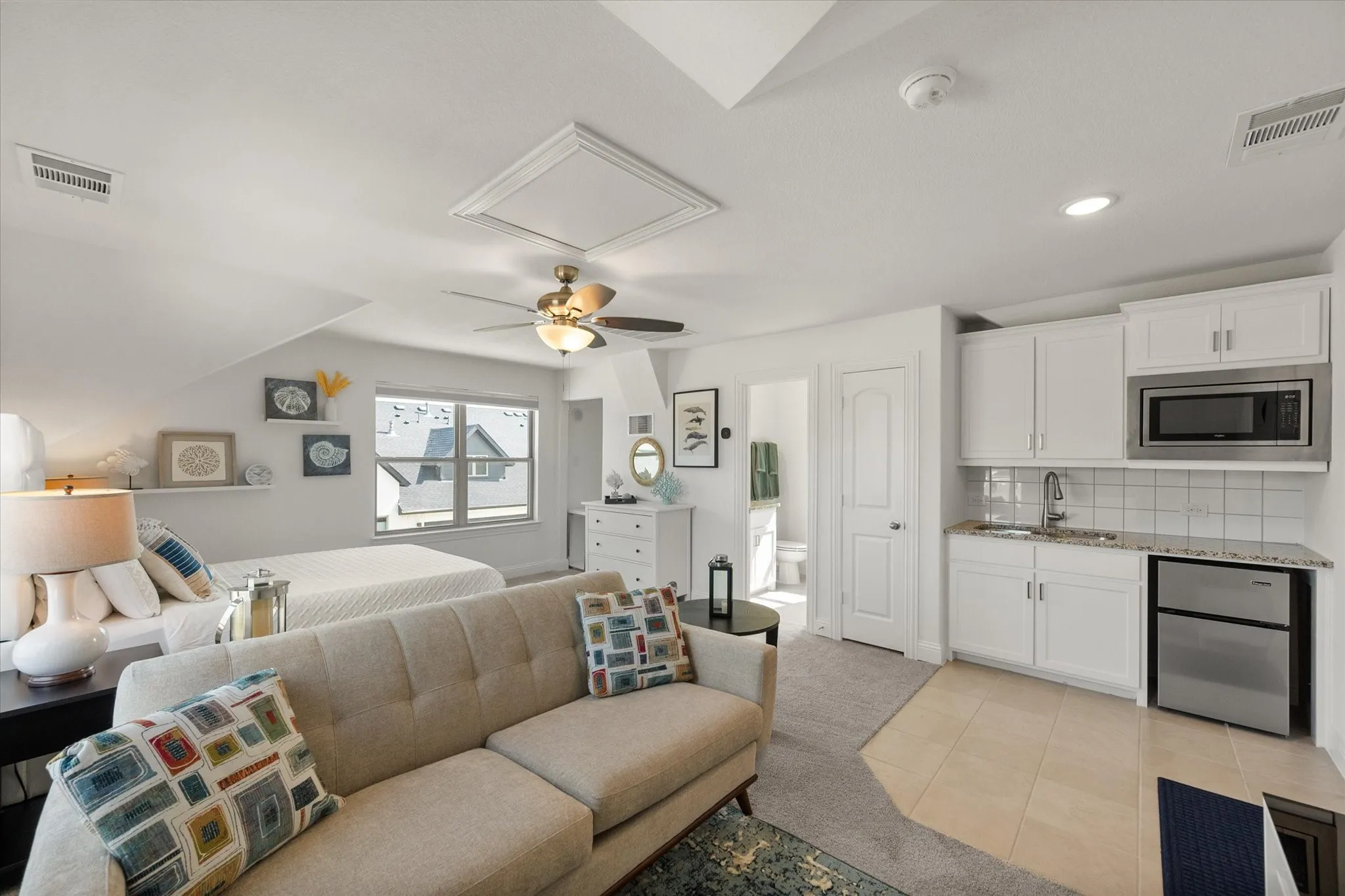 Upstairs Garage Studio Bedroom featuring stainless steel fridge, microwave, bathroom, light carpet, light tile patterned floors, recessed lighting, and a ceiling fan