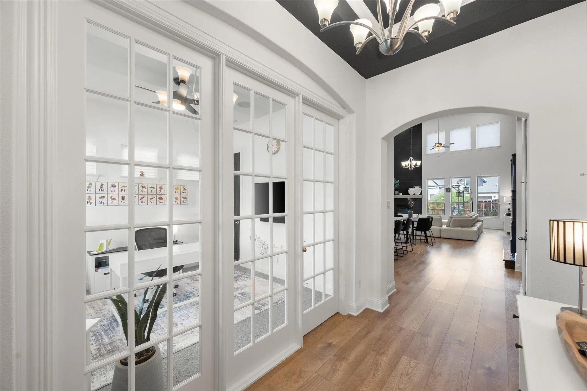 Corridor featuring arched walkways, a chandelier, and light wood-style flooring