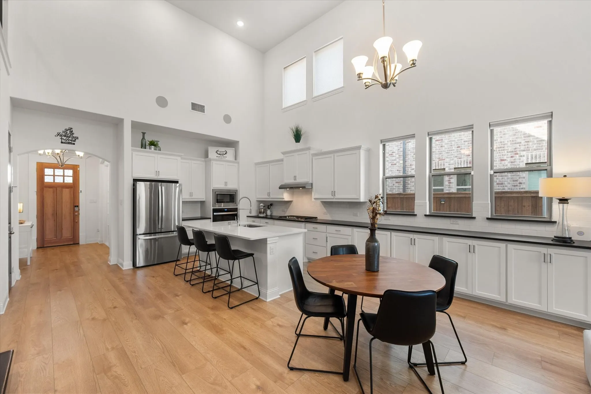 Dining area with a chandelier, plenty of natural light, light wood-type flooring, and a high ceiling