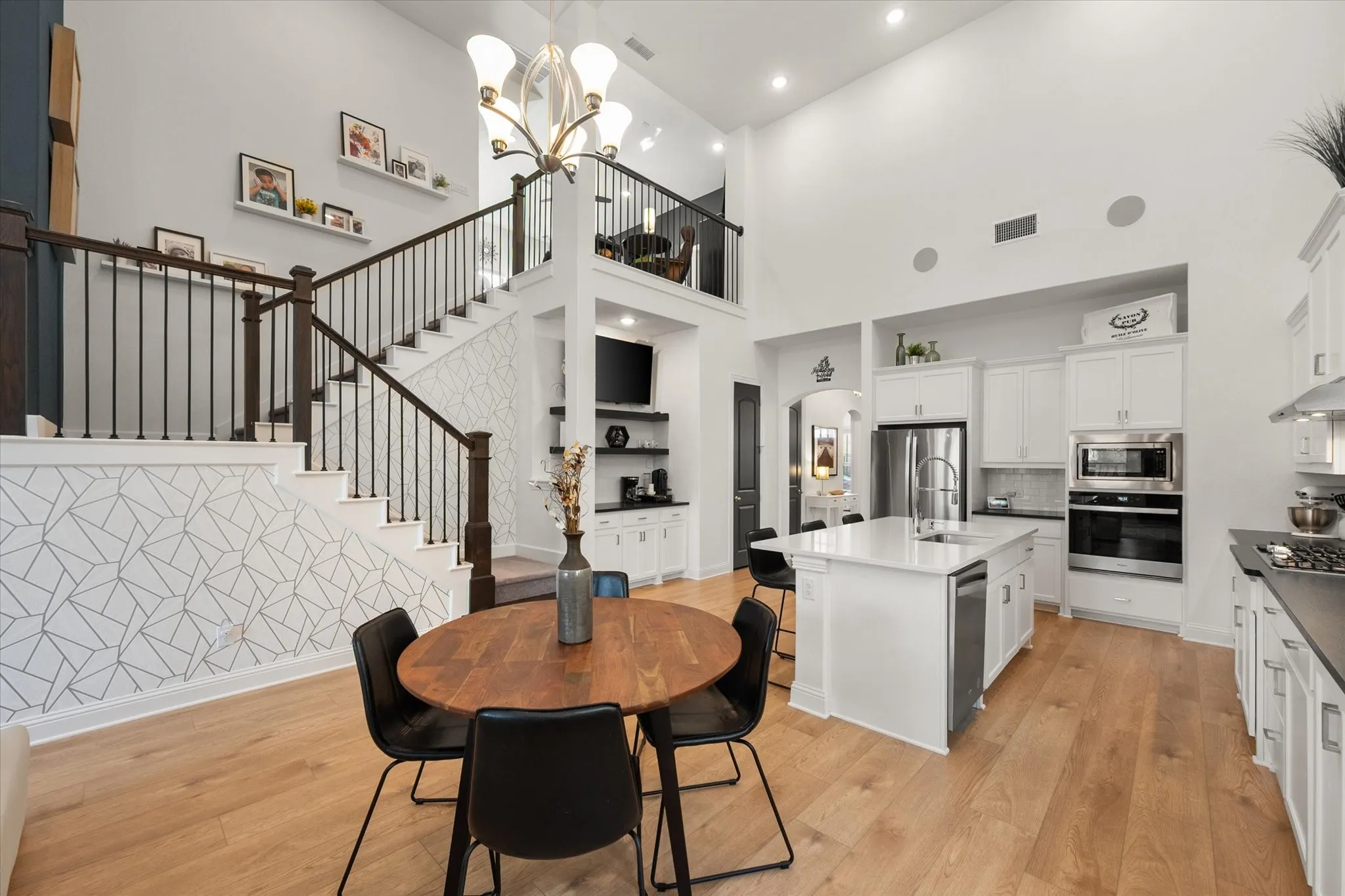 Dining area with arched walkways, a towering ceiling, recessed lighting, light wood-type flooring, and stairs