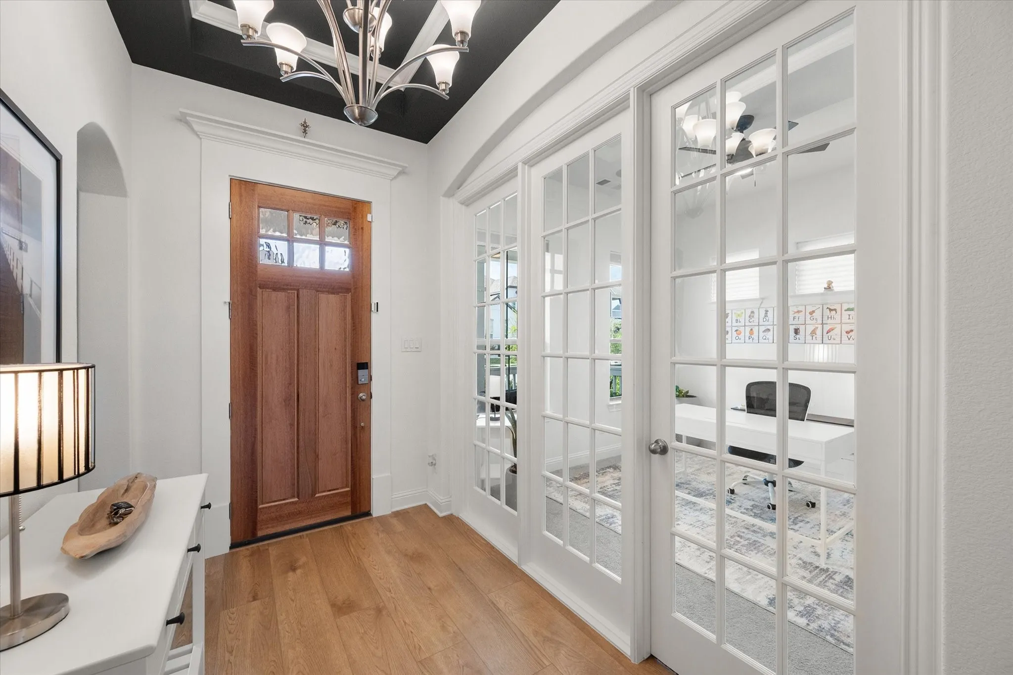 Entrance foyer with a chandelier, light wood-style floors, french doors, and arched walkways
