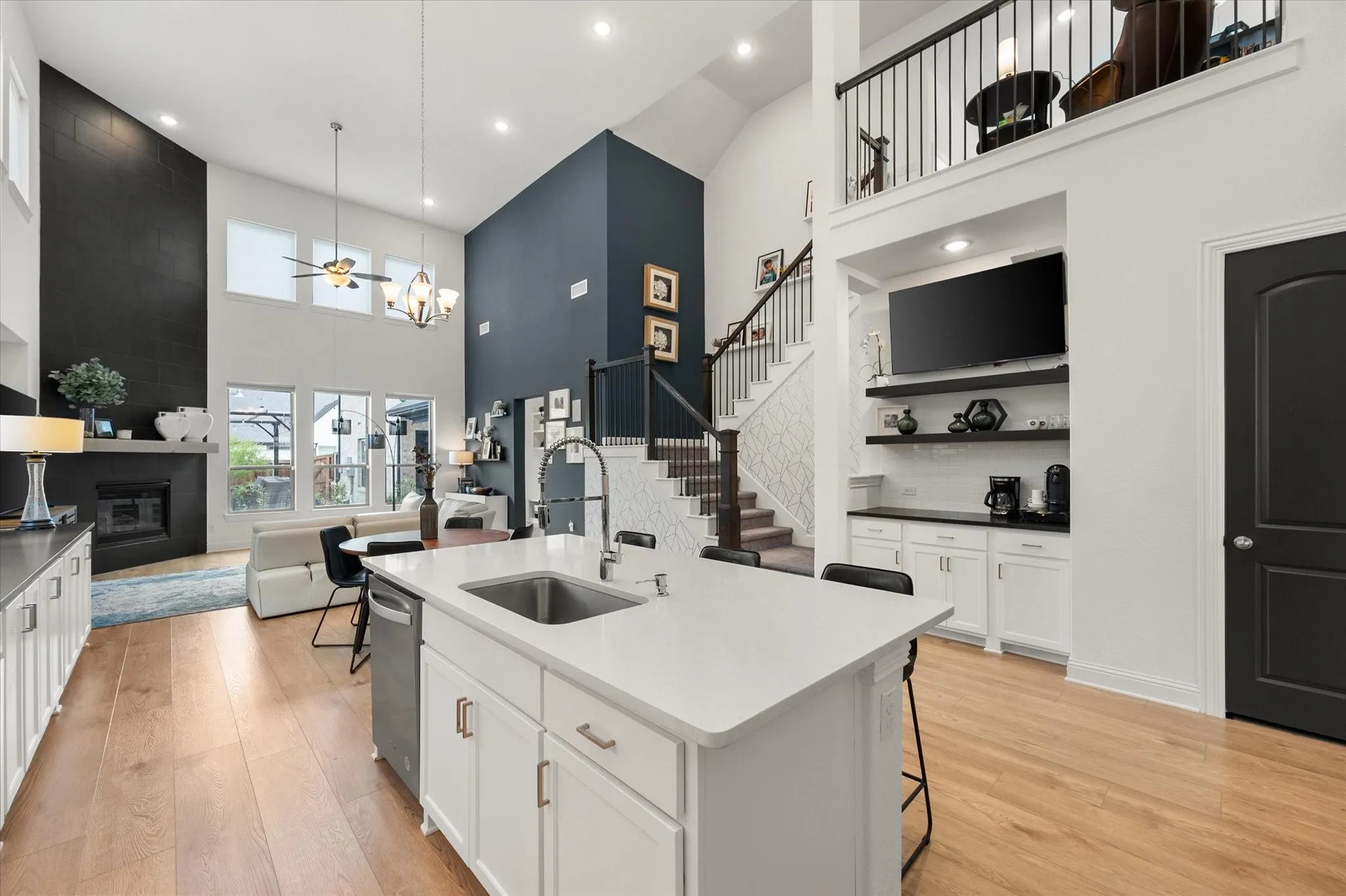 Kitchen with a towering ceiling, a breakfast bar area, white cabinetry, open shelves, and a fireplace