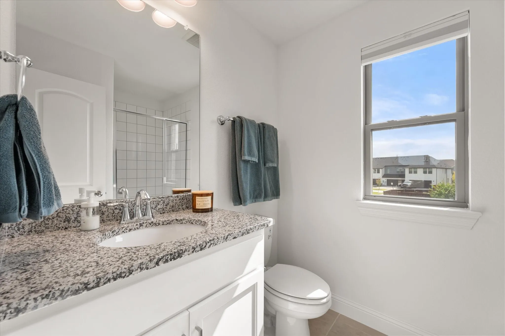 Upstairs Studio bathroom featuring vanity, light tile patterned flooring, and a shower stall