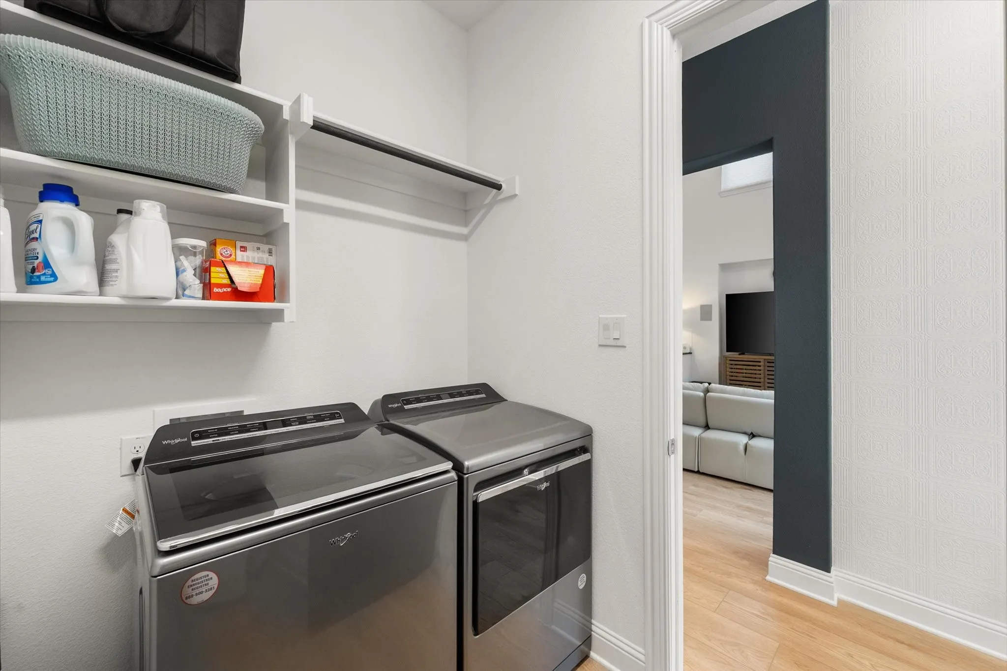 Washroom with light wood-type flooring and washing machine and dryer