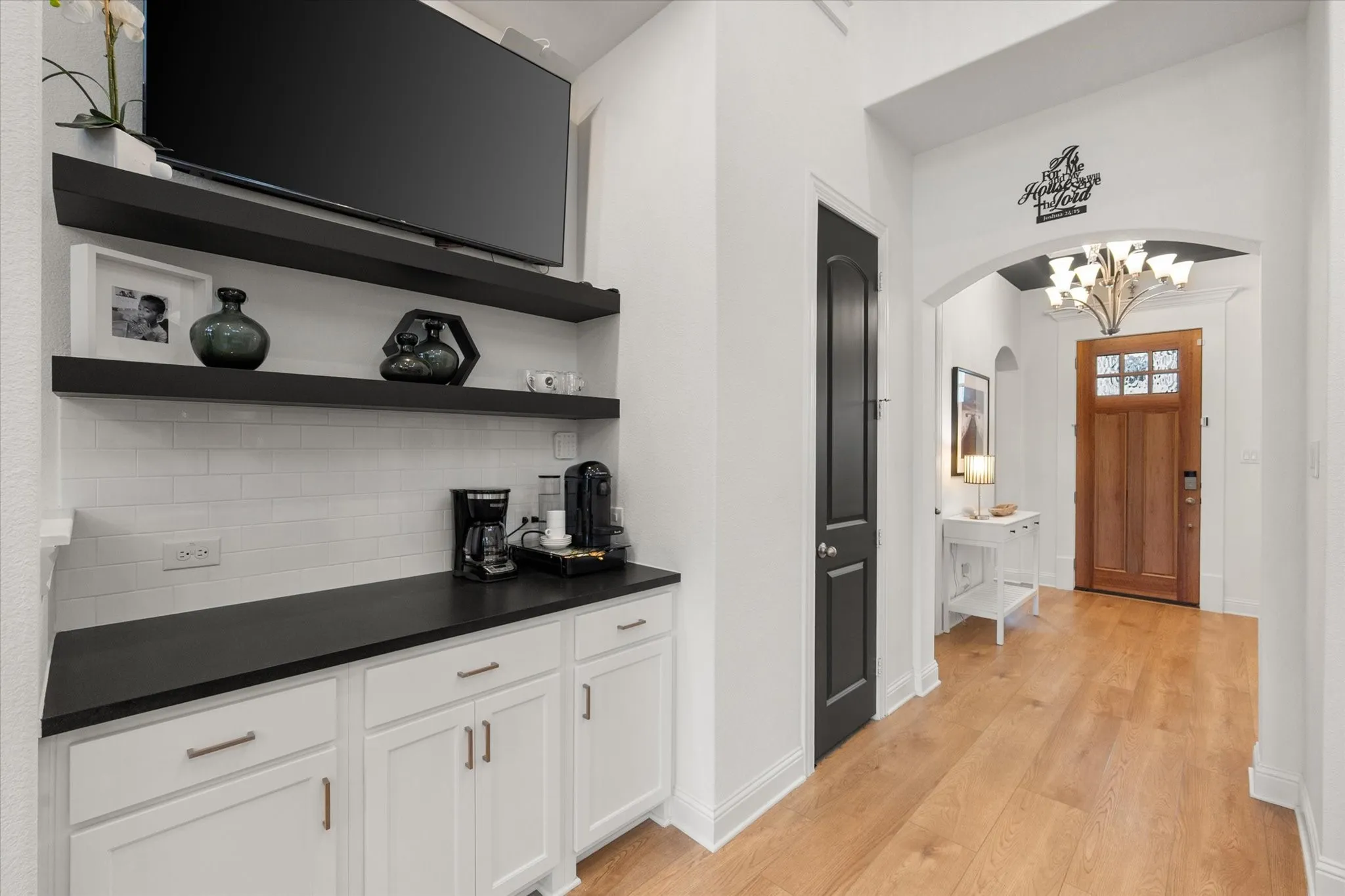 Desk area with open shelves, dark countertops, arched walkways, light wood-style floors, and tasteful backsplash