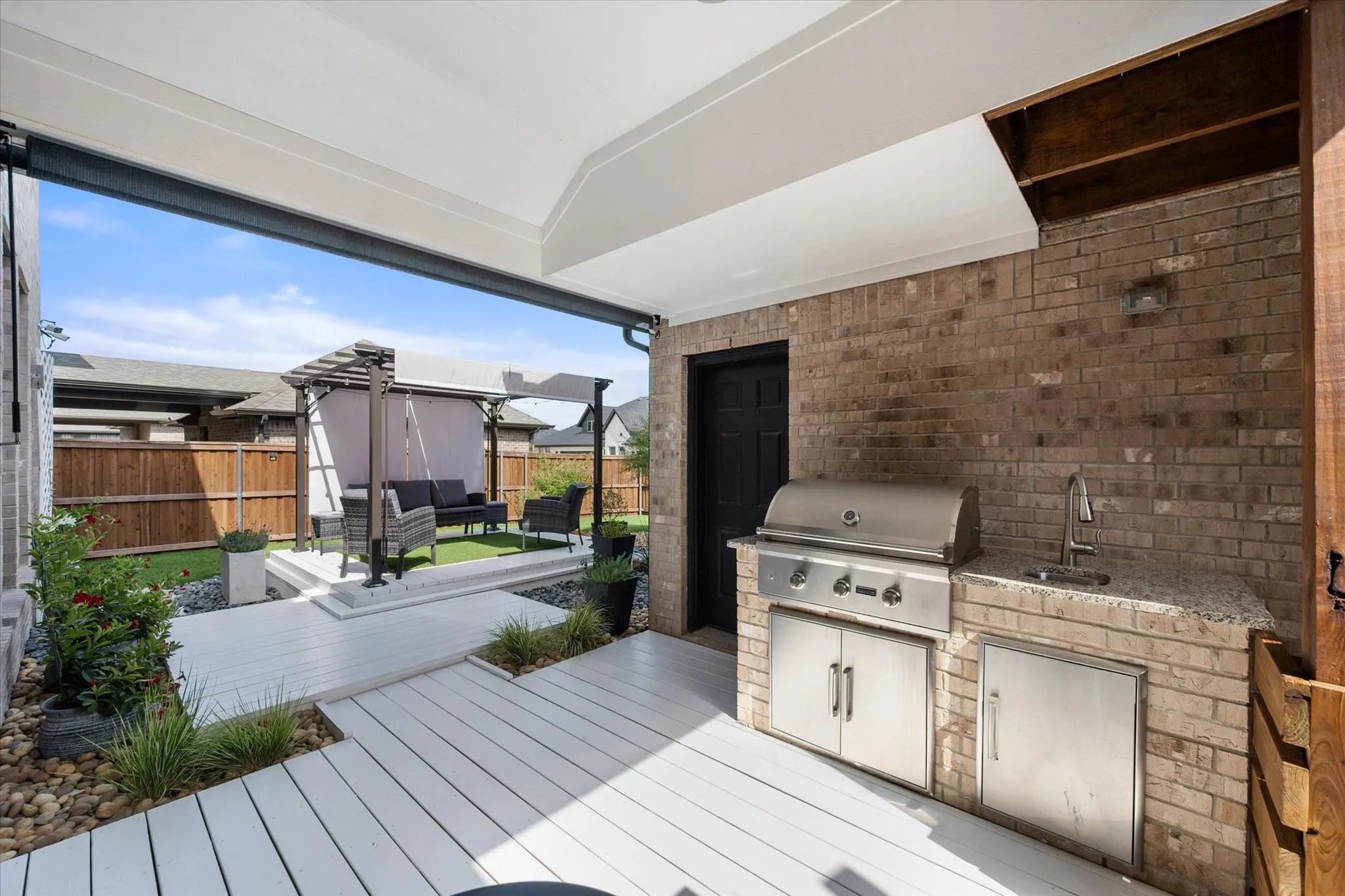 Wooden deck surrounded with high quality astro-turf, beautiful pergola, drought resistant landscaping and a covered patio area with outside living area,grill and sink.