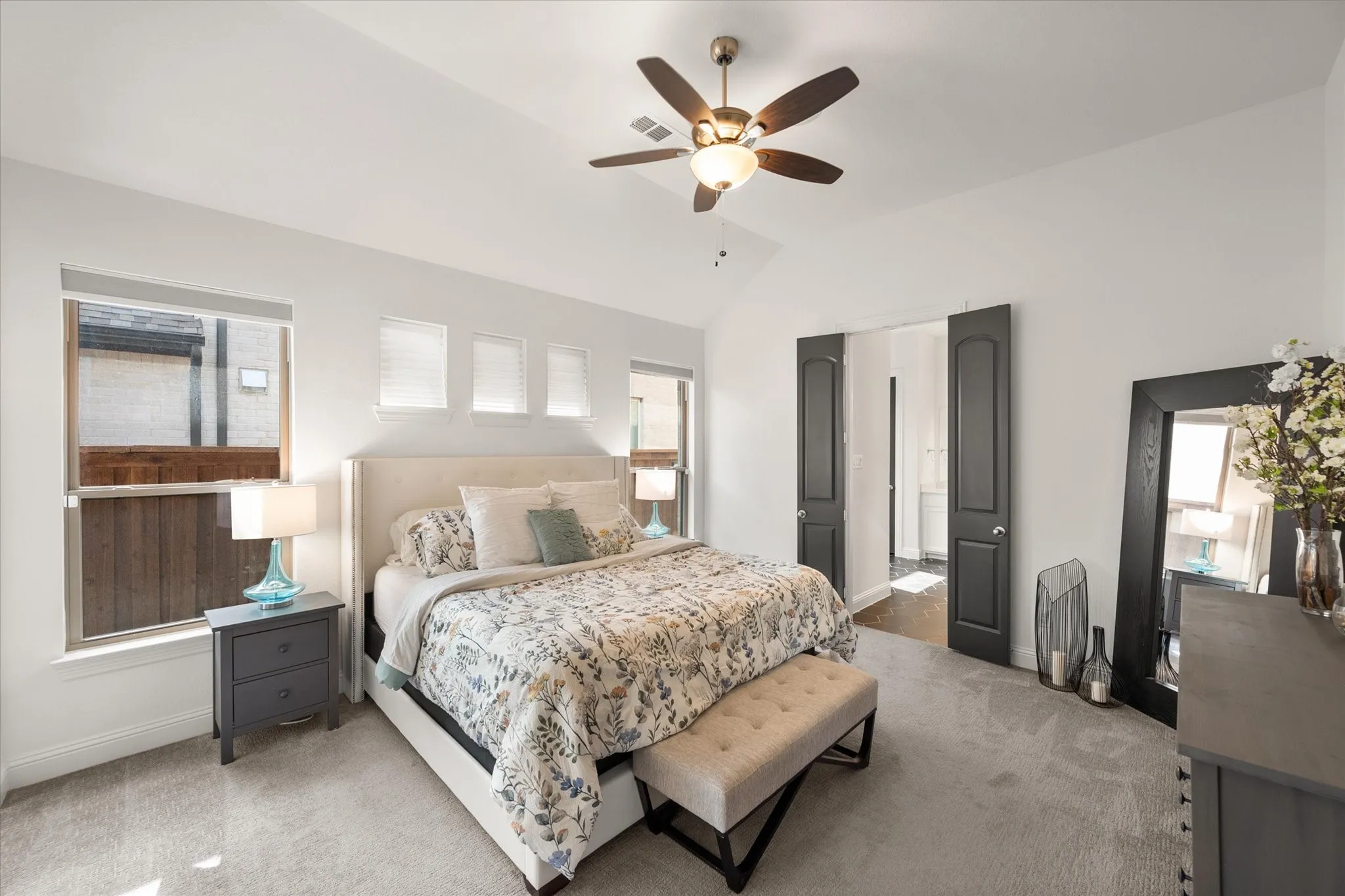Bedroom with carpet flooring, lofted ceiling, ensuite bathroom, ceiling fan, and multiple windows