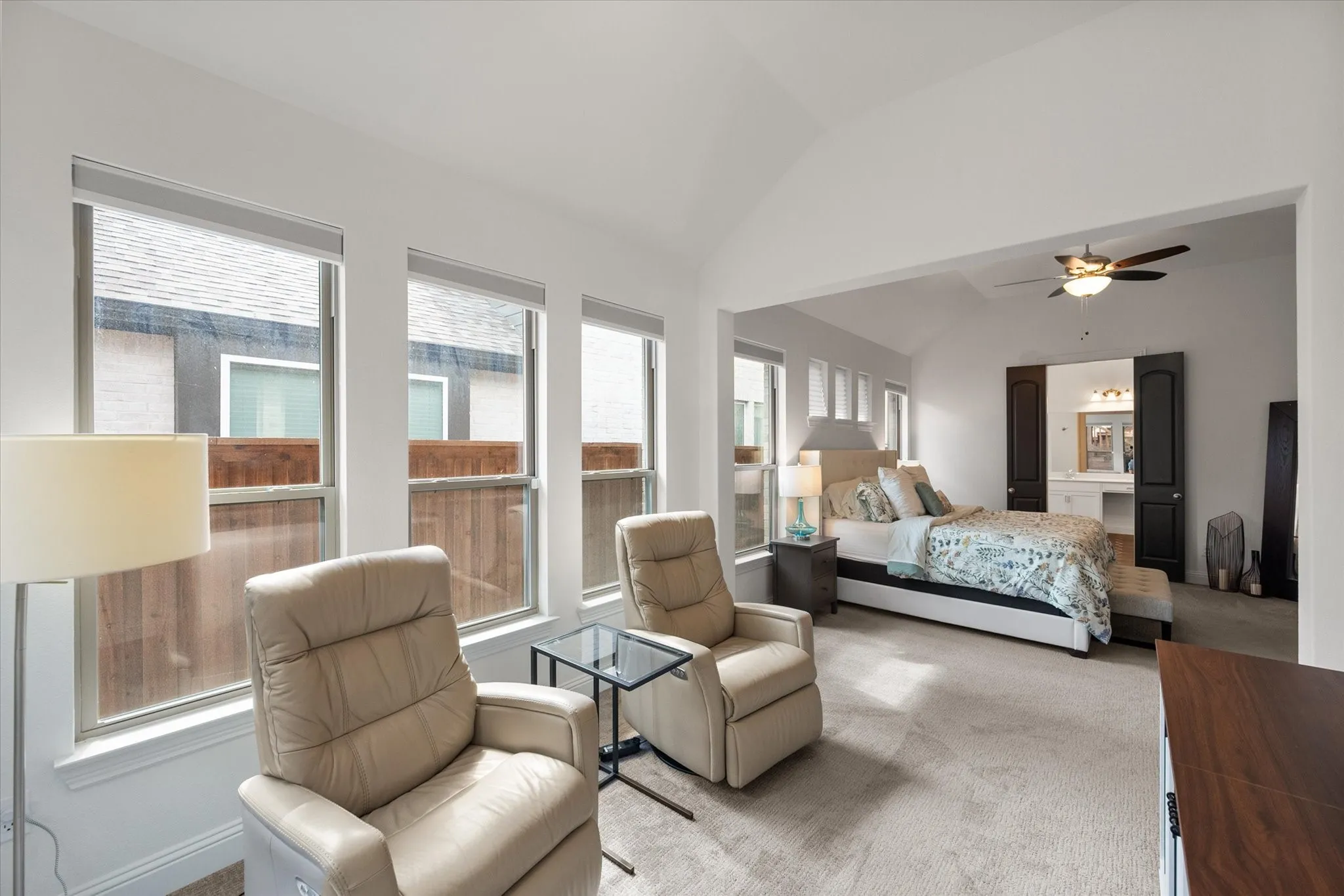 Carpeted bedroom featuring lofted ceiling, ensuite bath, and ceiling fan