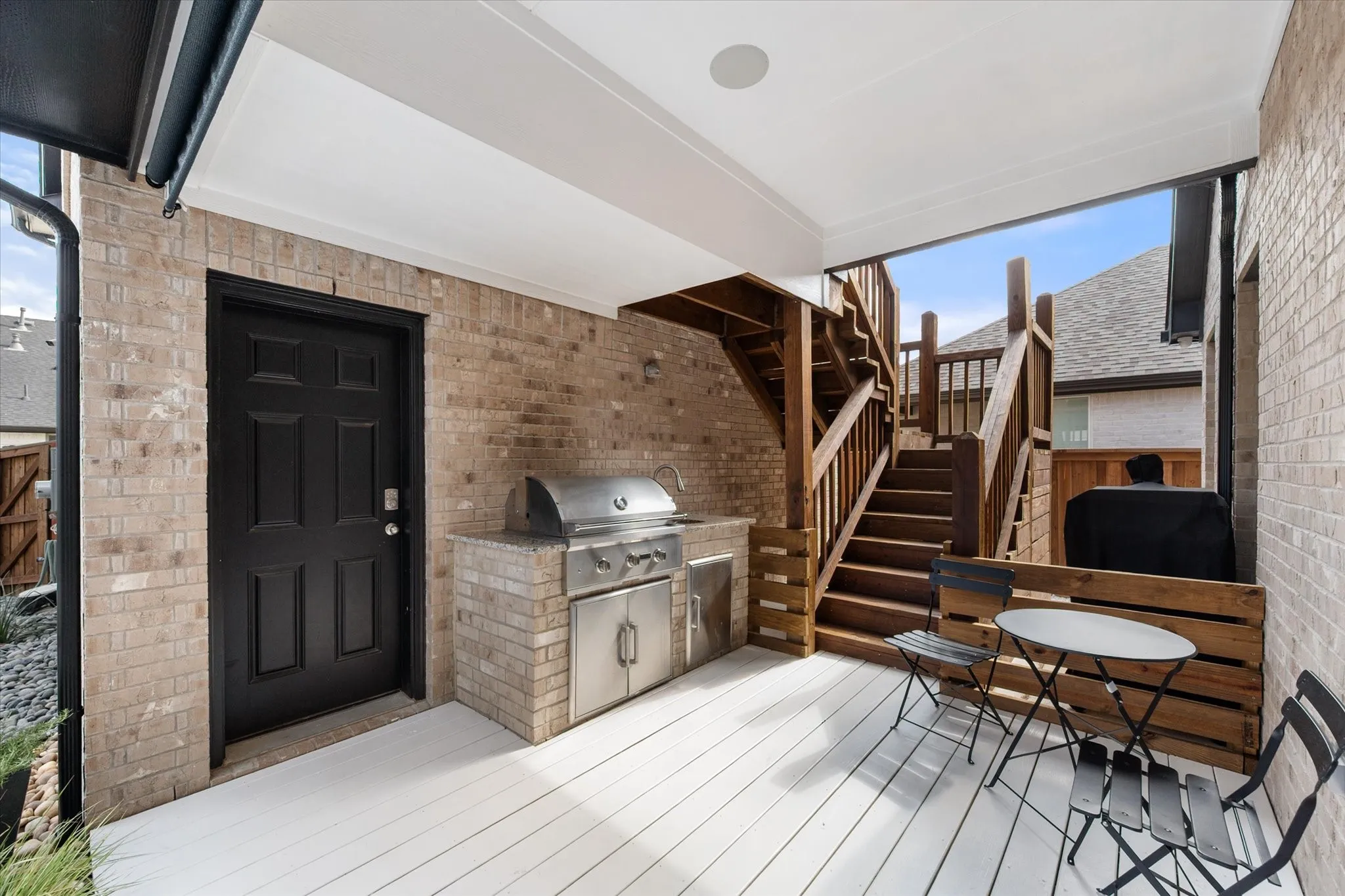 Wooden terrace with an outdoor kitchen and stairway leading to the garage studio living space