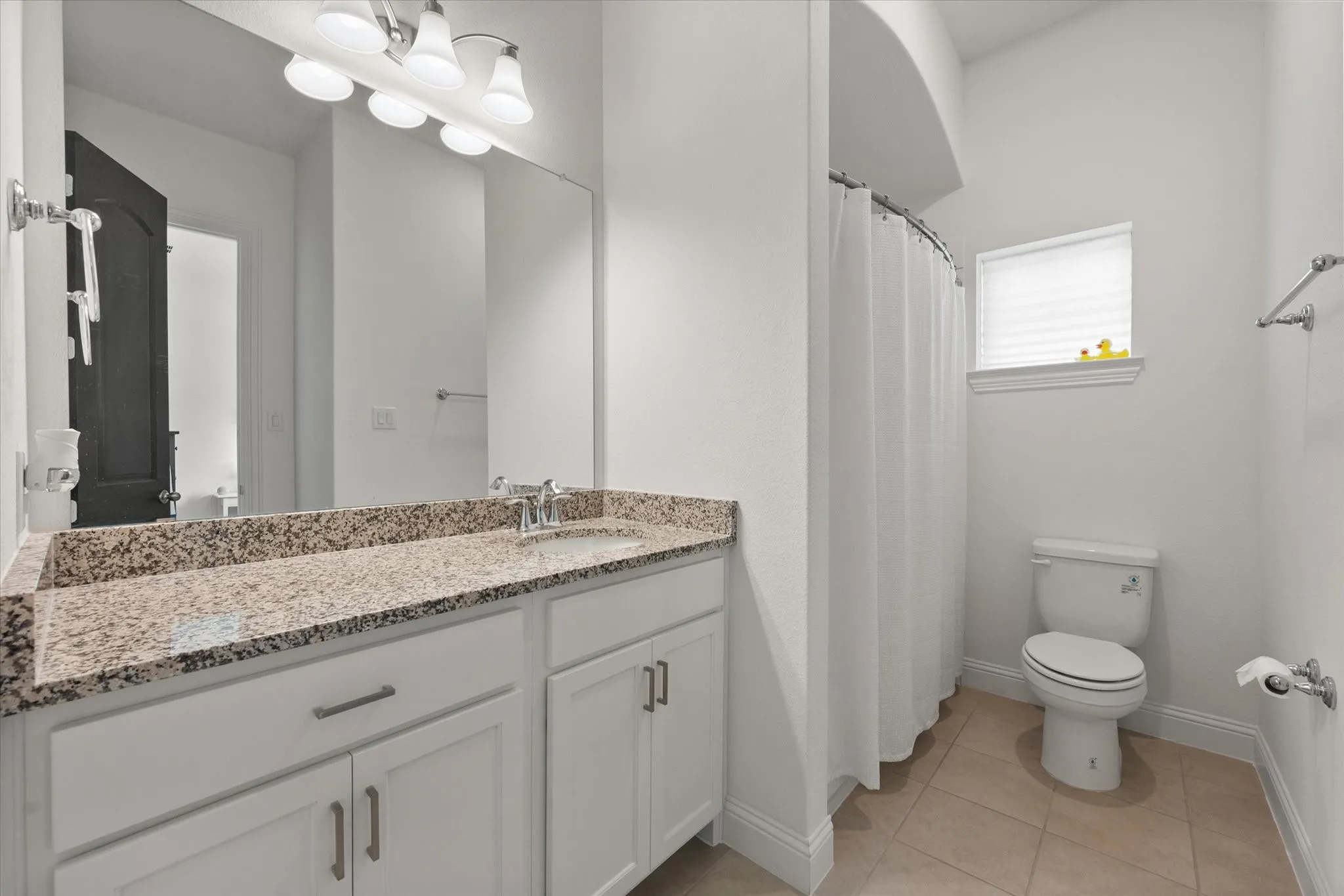 Secondary Bathroom on first floor featuring vanity, a shower with shower curtain, and light tile patterned floors