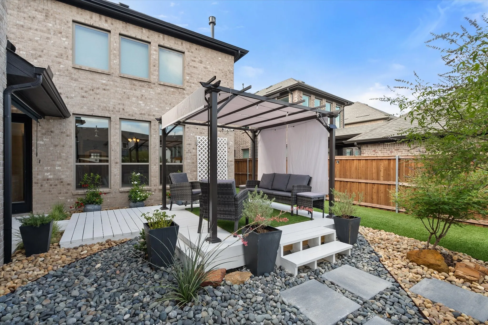 Back of house featuring brick siding, an outdoor gathering place, fenced backyard, and a patio