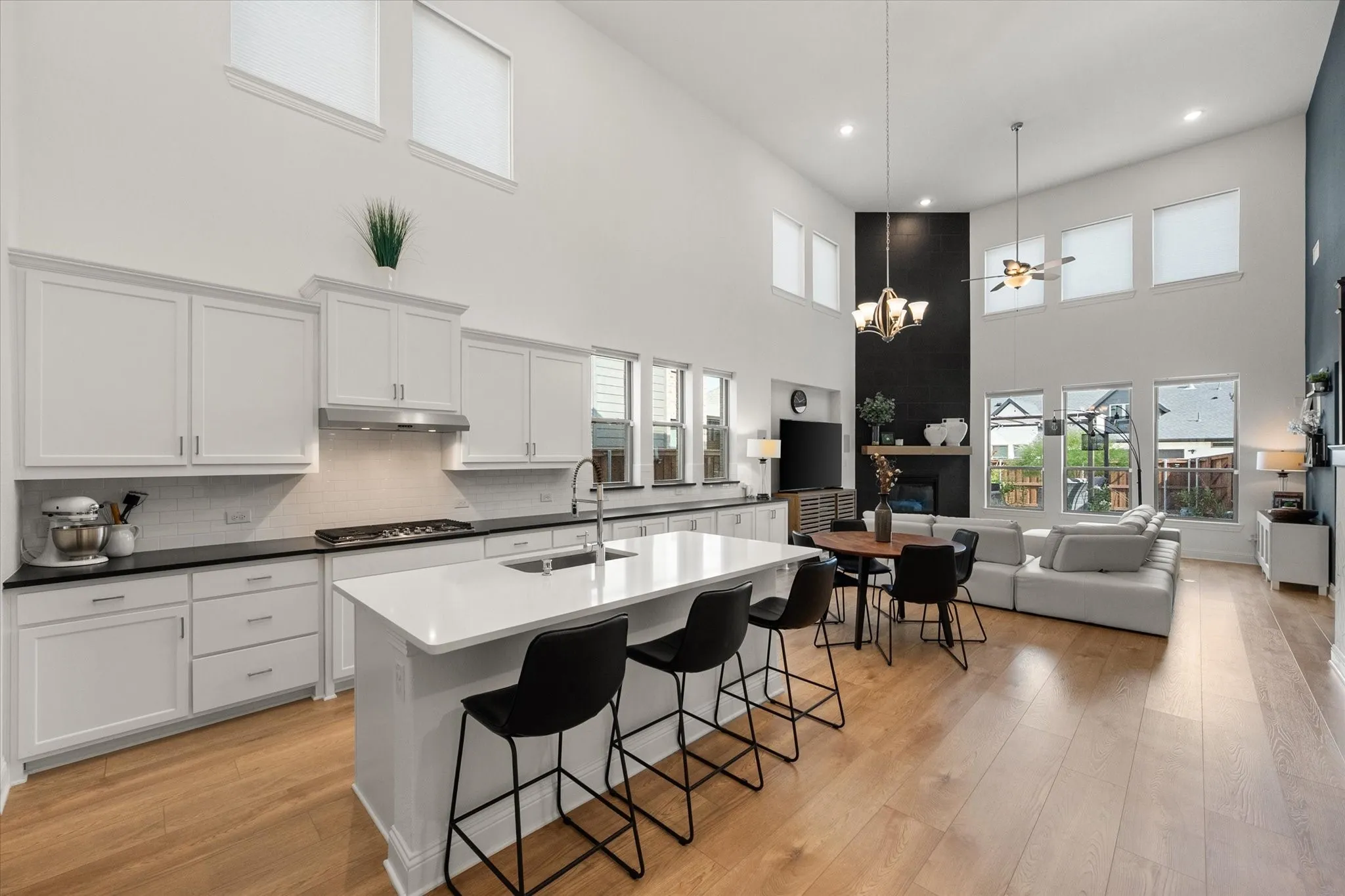 Kitchen with white cabinetry, a kitchen island with sink, a high ceiling, decorative light fixtures, and open floor plan