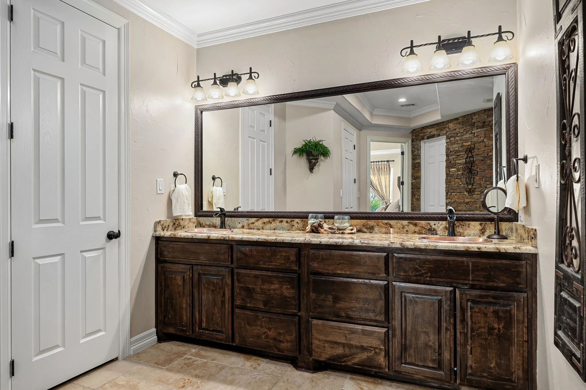 Bathroom featuring ornamental molding, double vanity with cast iron sinks , stone tile floors, and a shower stall