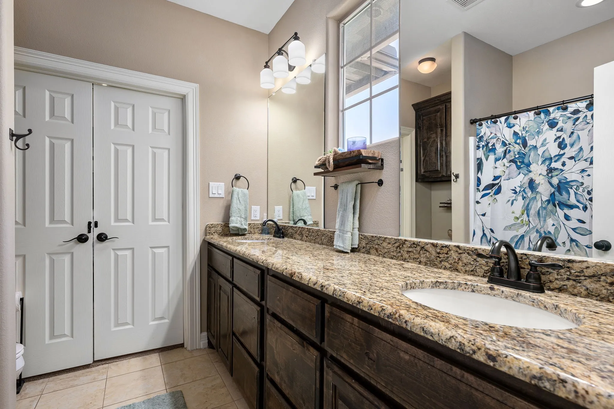Bathroom featuring double vanity, a shower with shower curtain, and light tile patterned floors