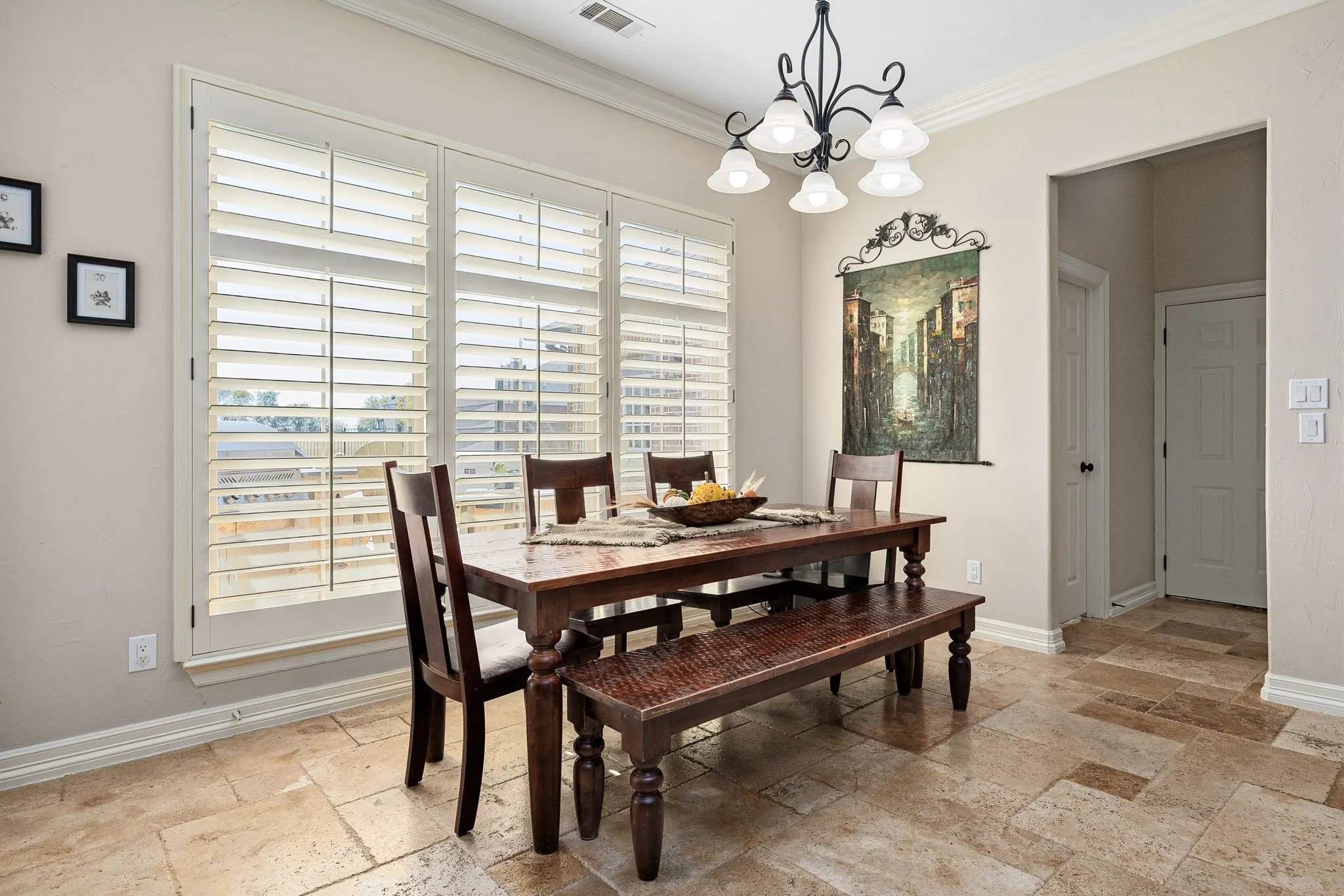 Dining area with stone tile floors, a chandelier, and crown molding