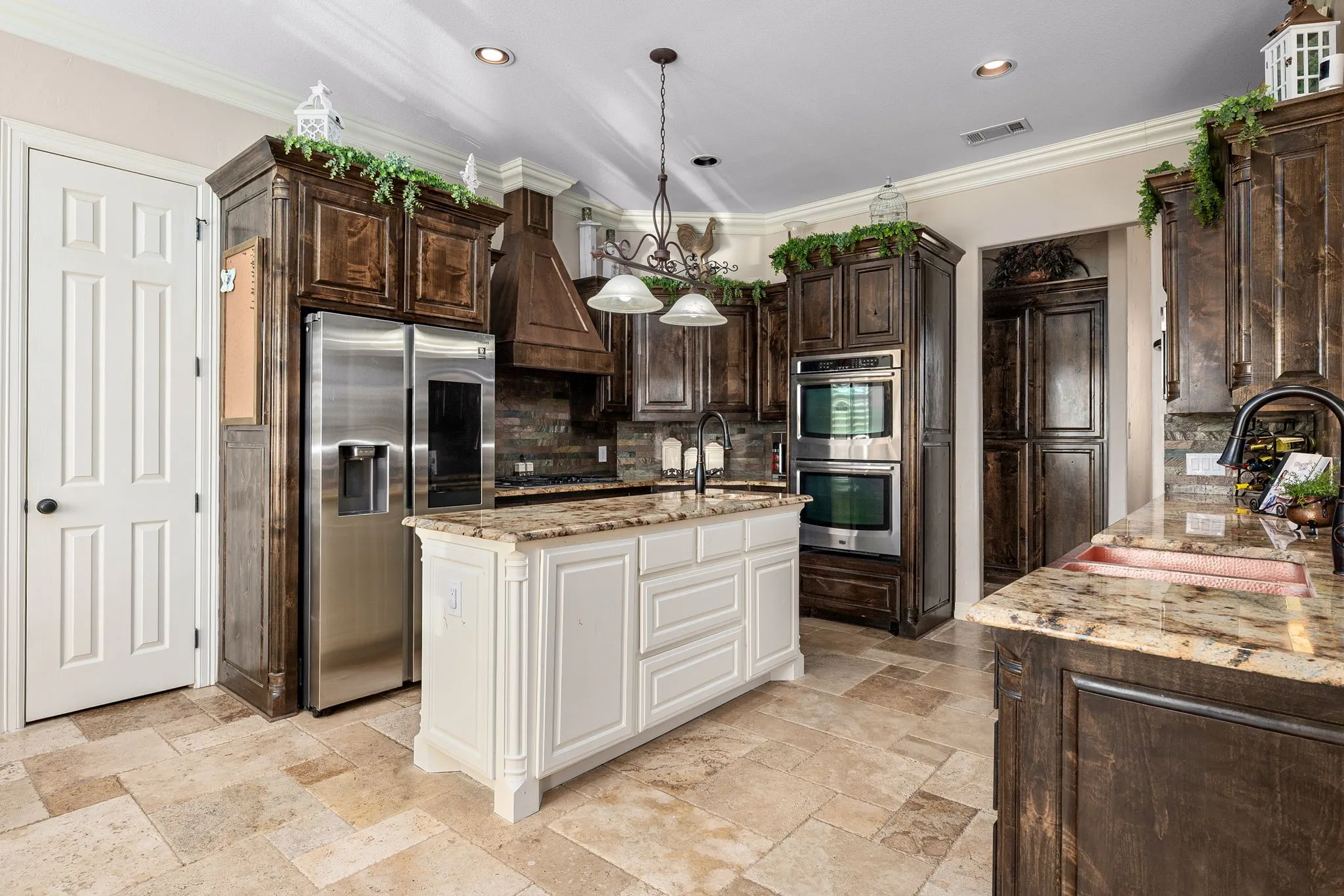 Kitchen featuring dark brown cabinetry, stainless steel appliances, hanging light fixtures, and crown molding