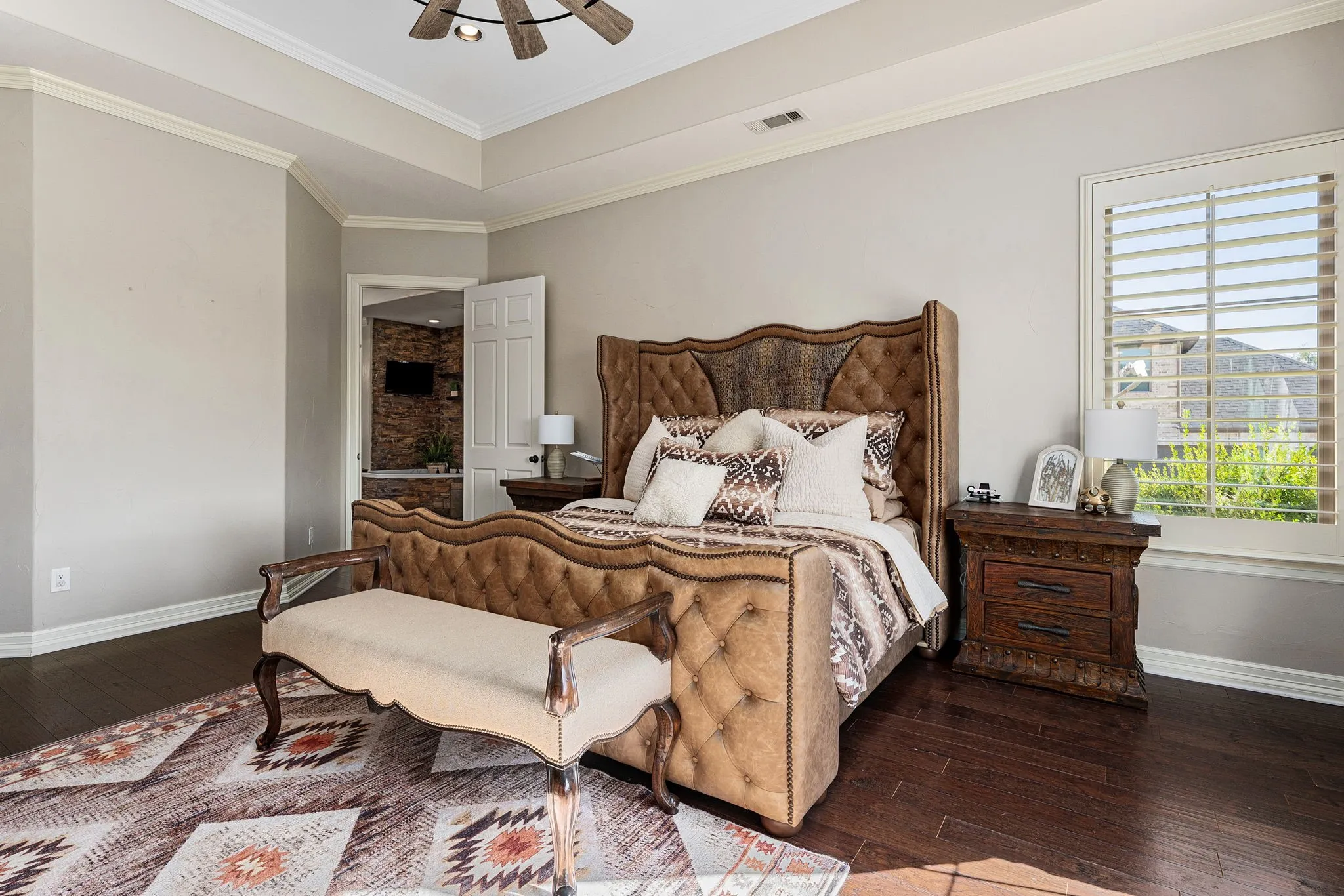 Bedroom with dark wood-style flooring, ceiling fan, a raised ceiling, and crown molding