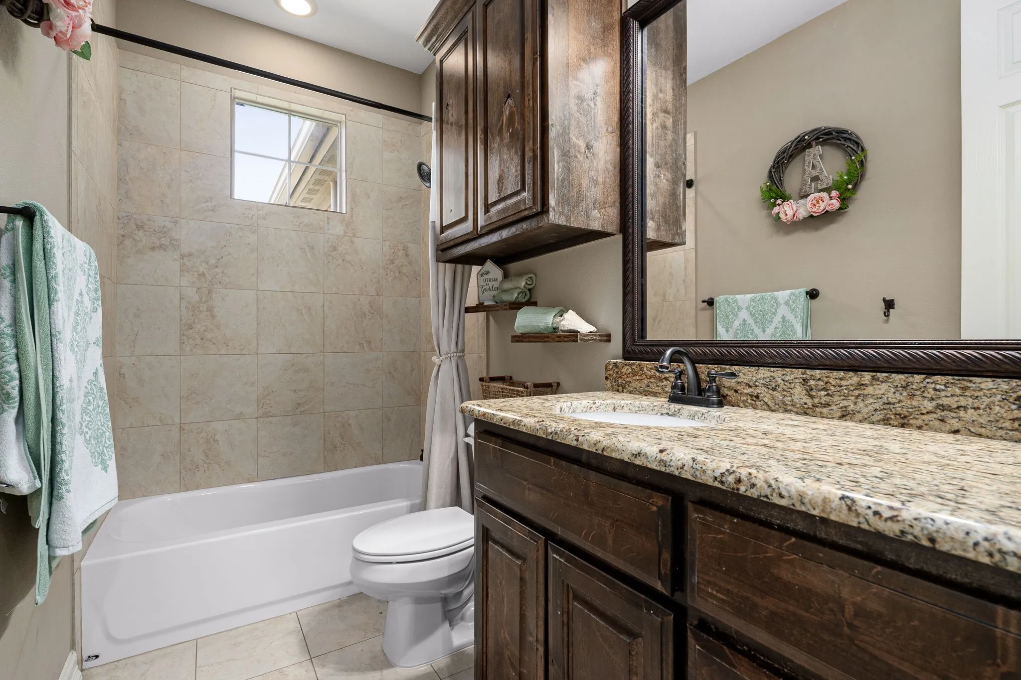 Full bath featuring vanity, shower / bath combo with shower curtain, and light tile patterned floors