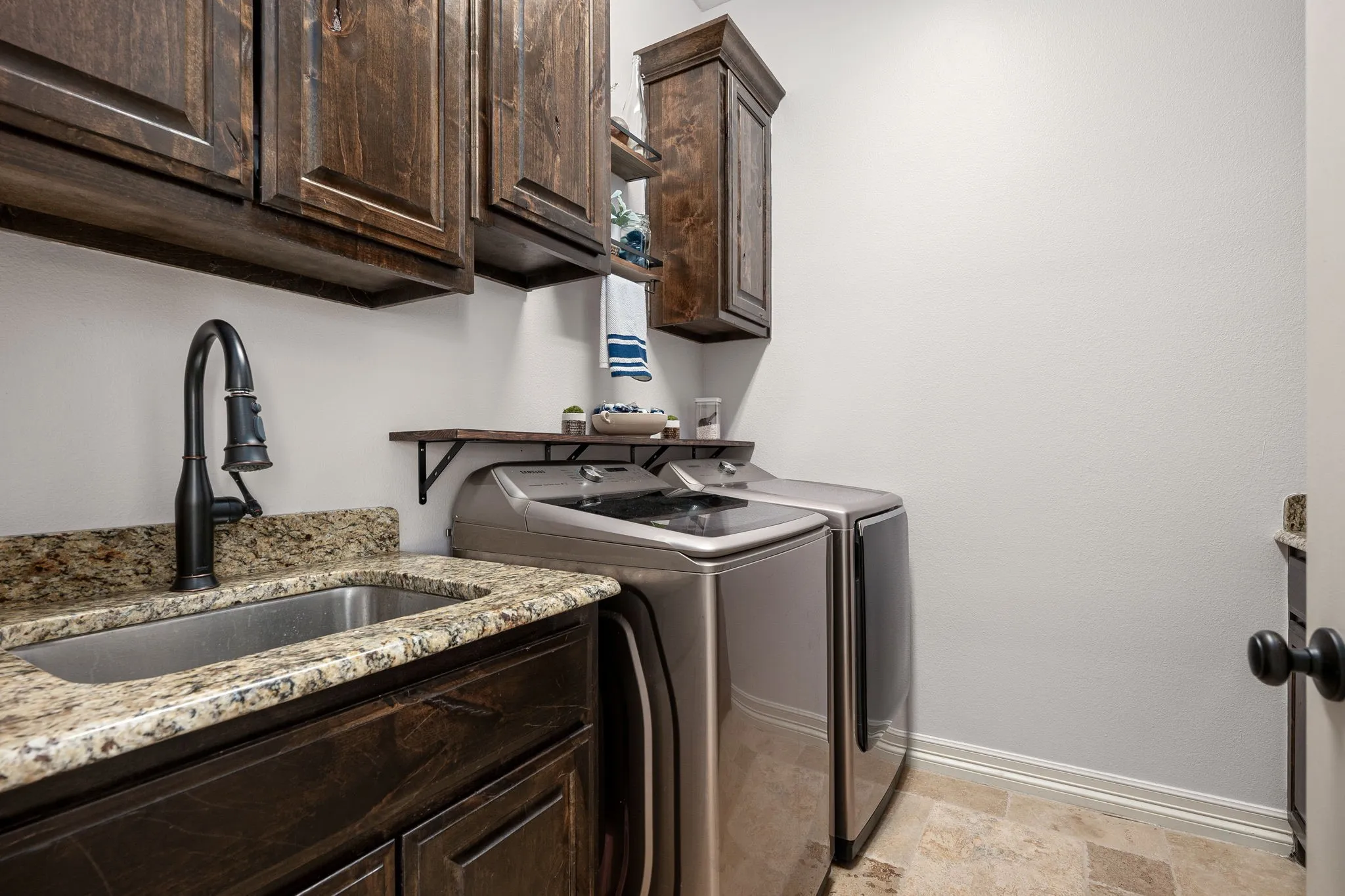 Washroom with stone finish floors, Sink,washing machine and dryer, and cabinet space